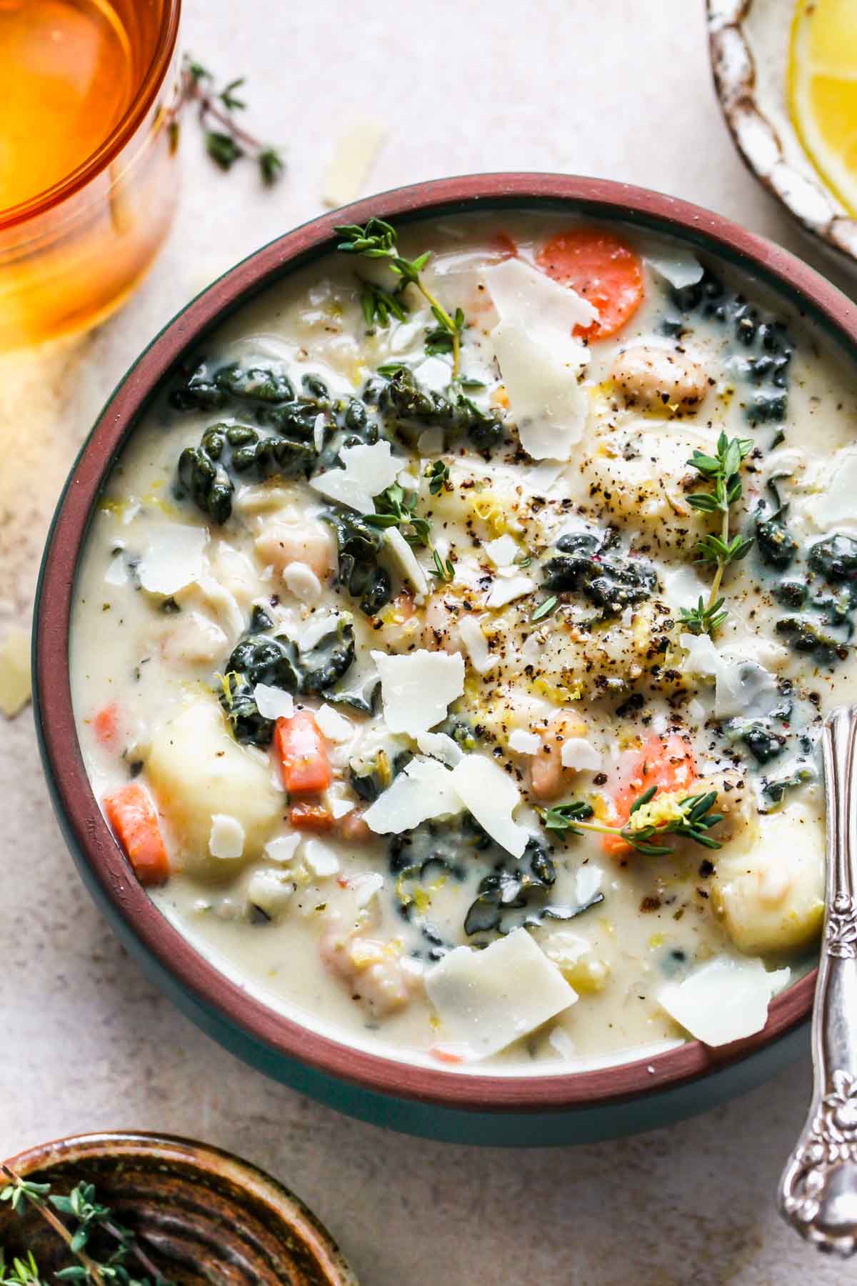 Creamy gnocchi soup in a bowl topped with parmesan and thyme