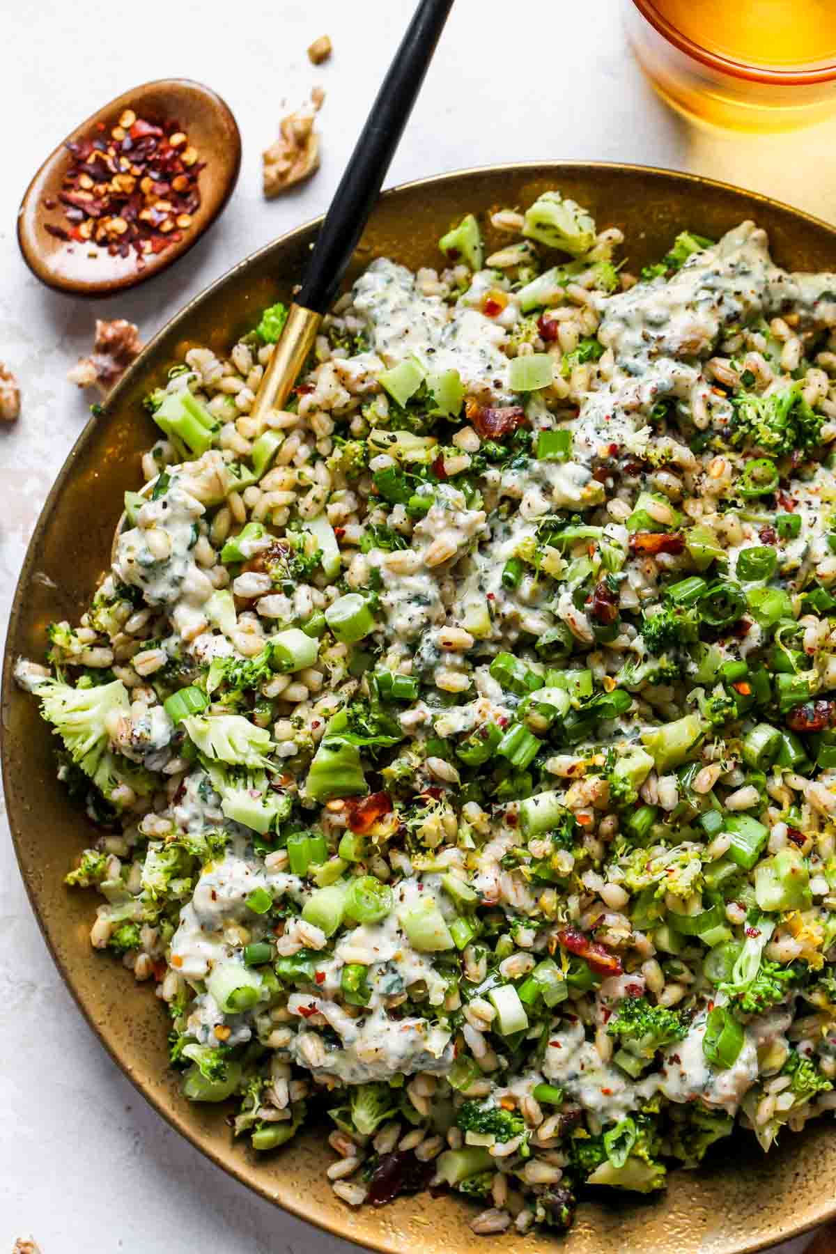 Grain salad being assembled and served on a gold platter