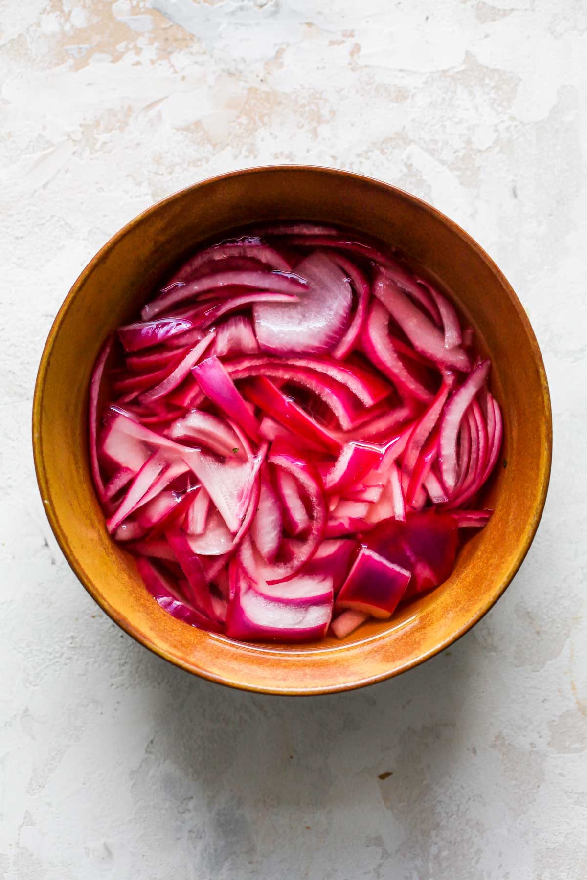Pickled red onions in a gold bowl