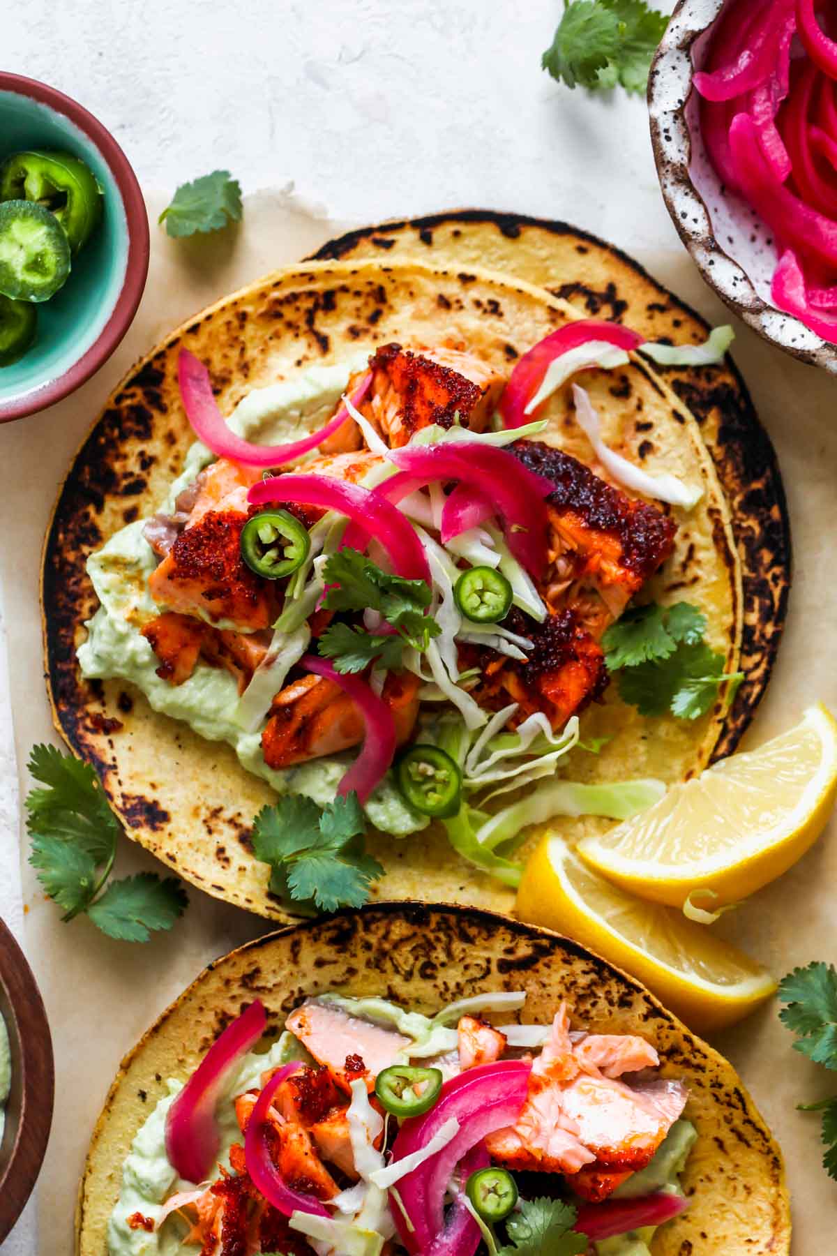 Salmon tacos with garnishes on a white platter.