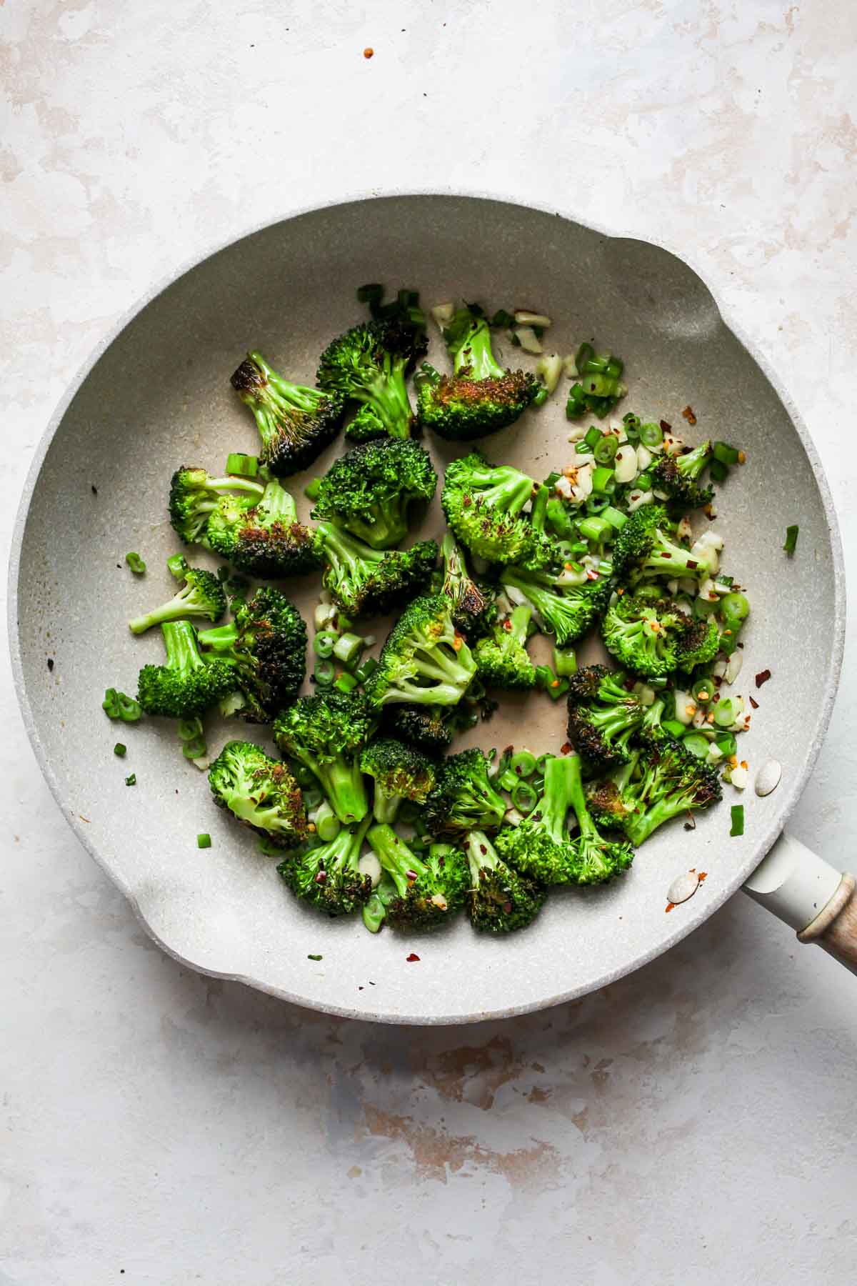 Broccoli, scallions, garlic, and chili flakes sautéing in a skillet
