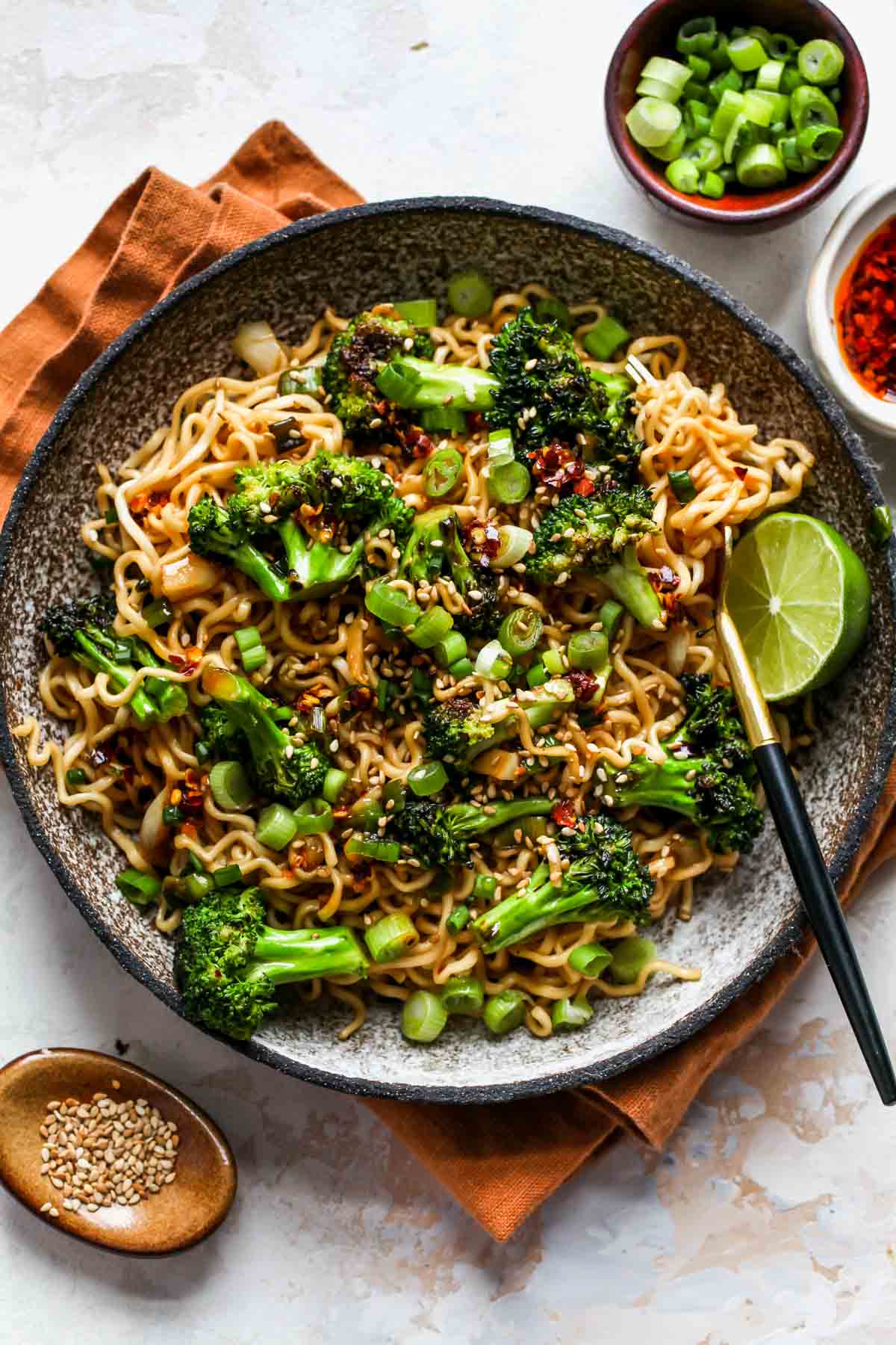 Scallion noodles with broccoli in a bowl topped with sesame seeds