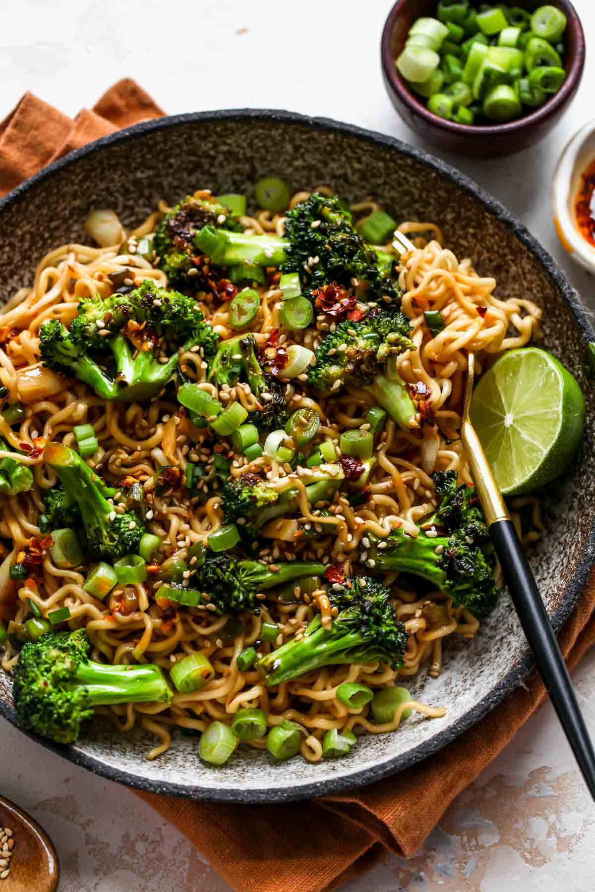 Noodles, broccoli, and garlic butter sauce in a bowl topped with sesame seeds and chili flakes