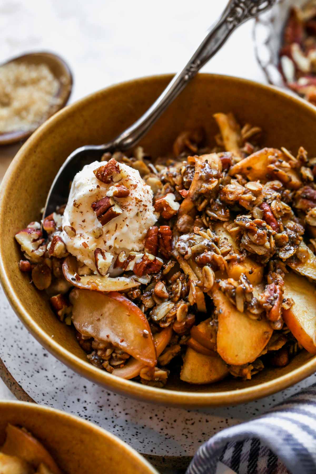Apple pie crisp in a gold bowl topped with a dollop of vanilla ice cream