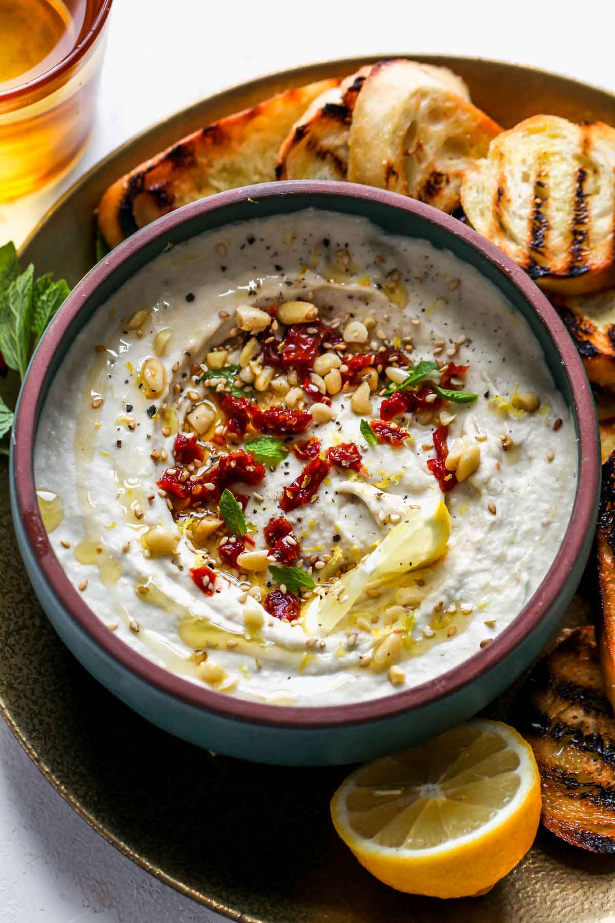 Creamy bean dip styled in a bowl surrounded by grilled bread for dipping