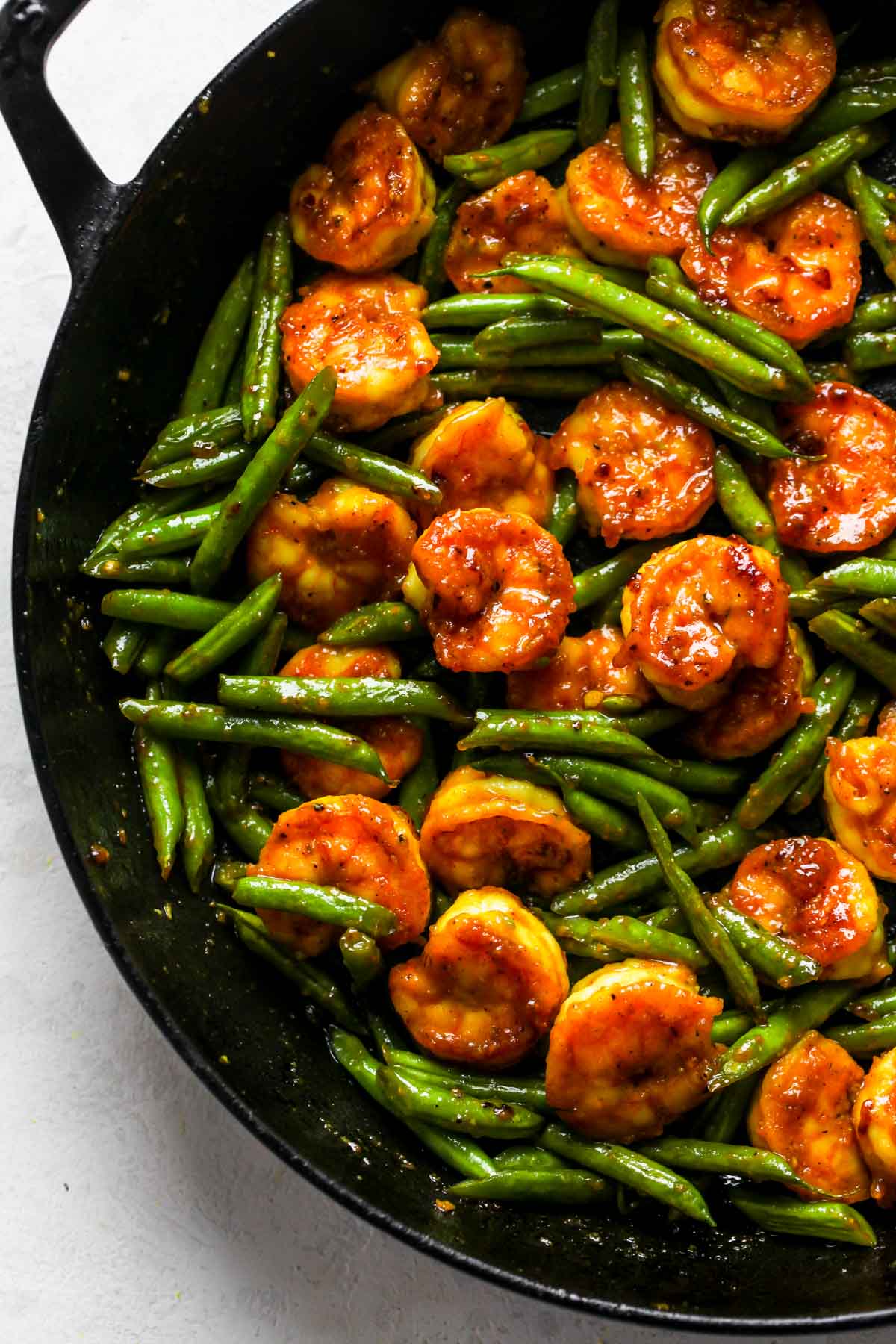 Black skillet filled with honey turmeric shrimp and green beans