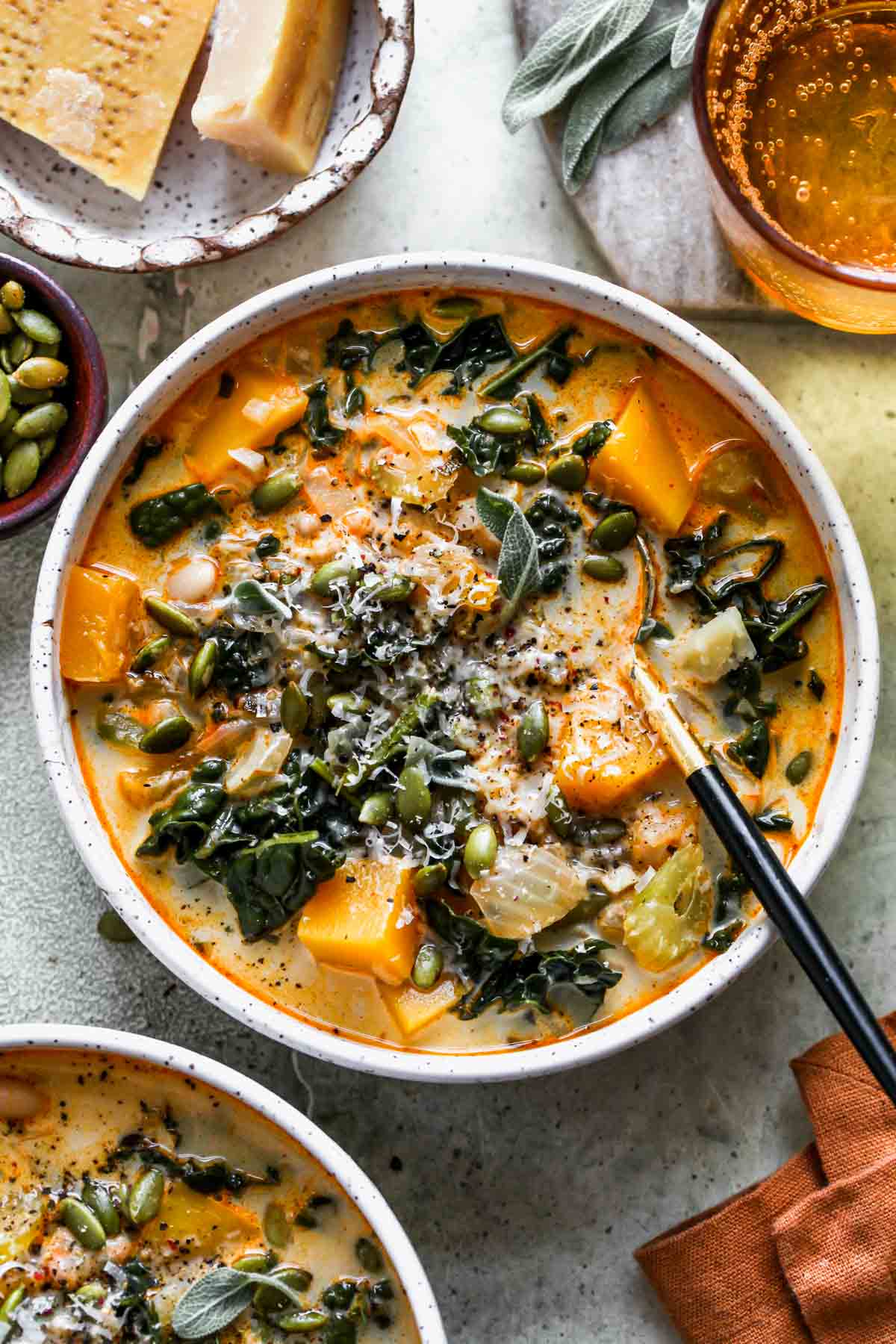 Butternut squash soup in a white bowl topped with pumpkin seeds and Parmesan.