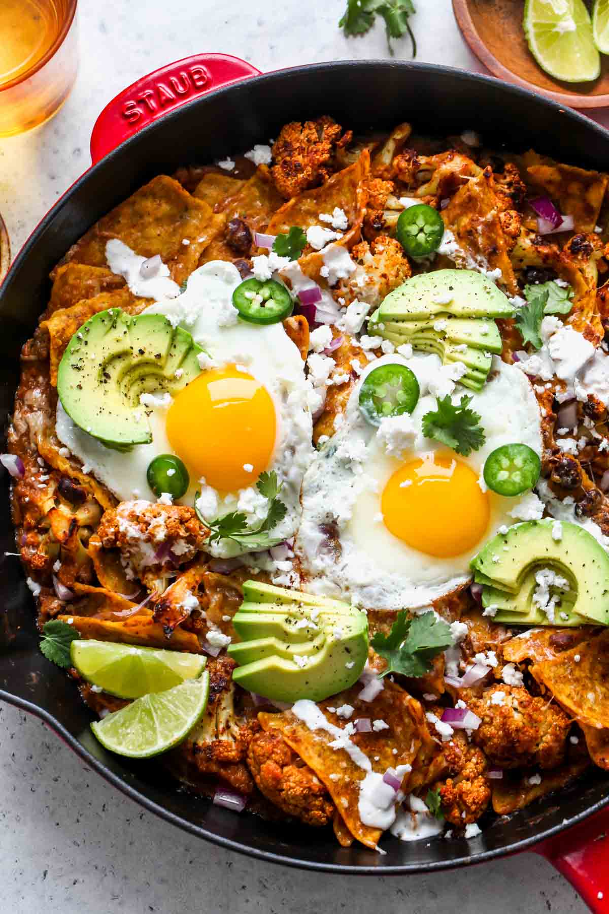 Chilaquiles in a skillet with cauliflower, black beans, and fried eggs