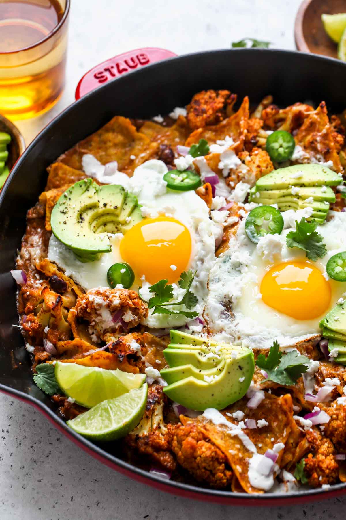 Cauliflower chilaquiles topped with fried eggs and avocado in a skillet