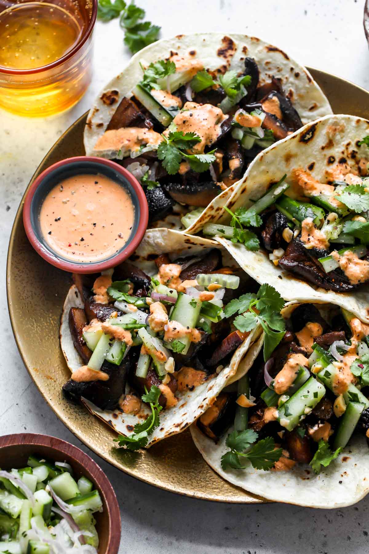 Eggplant and mushroom tacos styled on a gold plate with a bowl of kimchi cream on the side