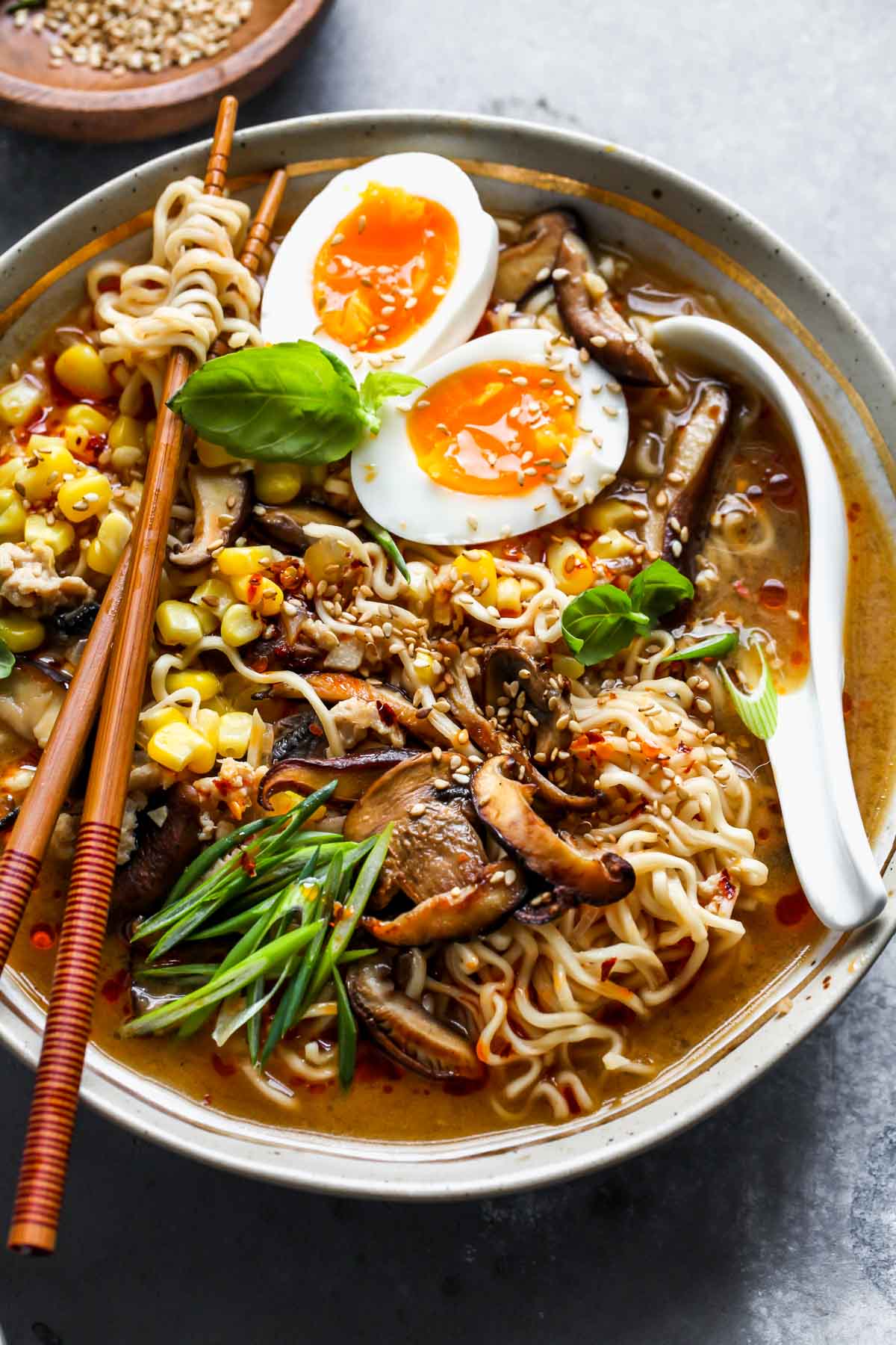 Spicy miso ramen styled in a bowl with a spoon resting on the right side and topped with garnishes.