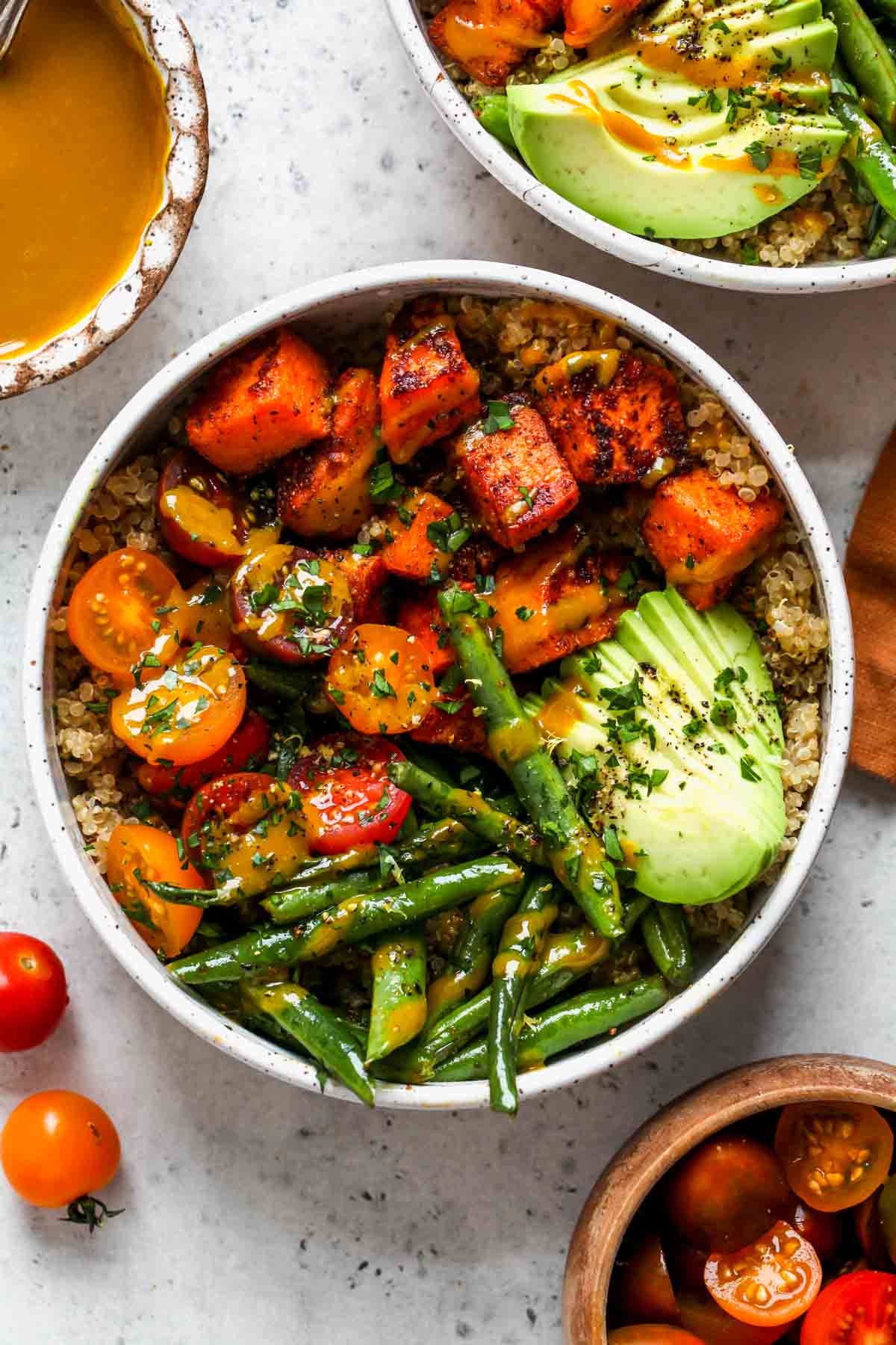 Roasted sweet potato bowls topped with avocado, tomatoes, and honey mustard sauce.