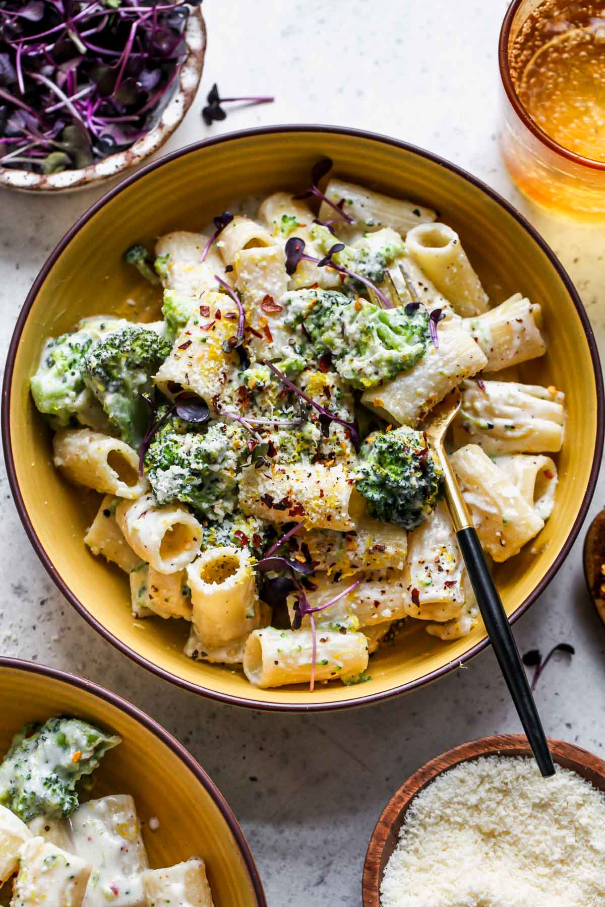 Lemon ricotta pasta with broccoli in a yellow bowl topped with parmesan