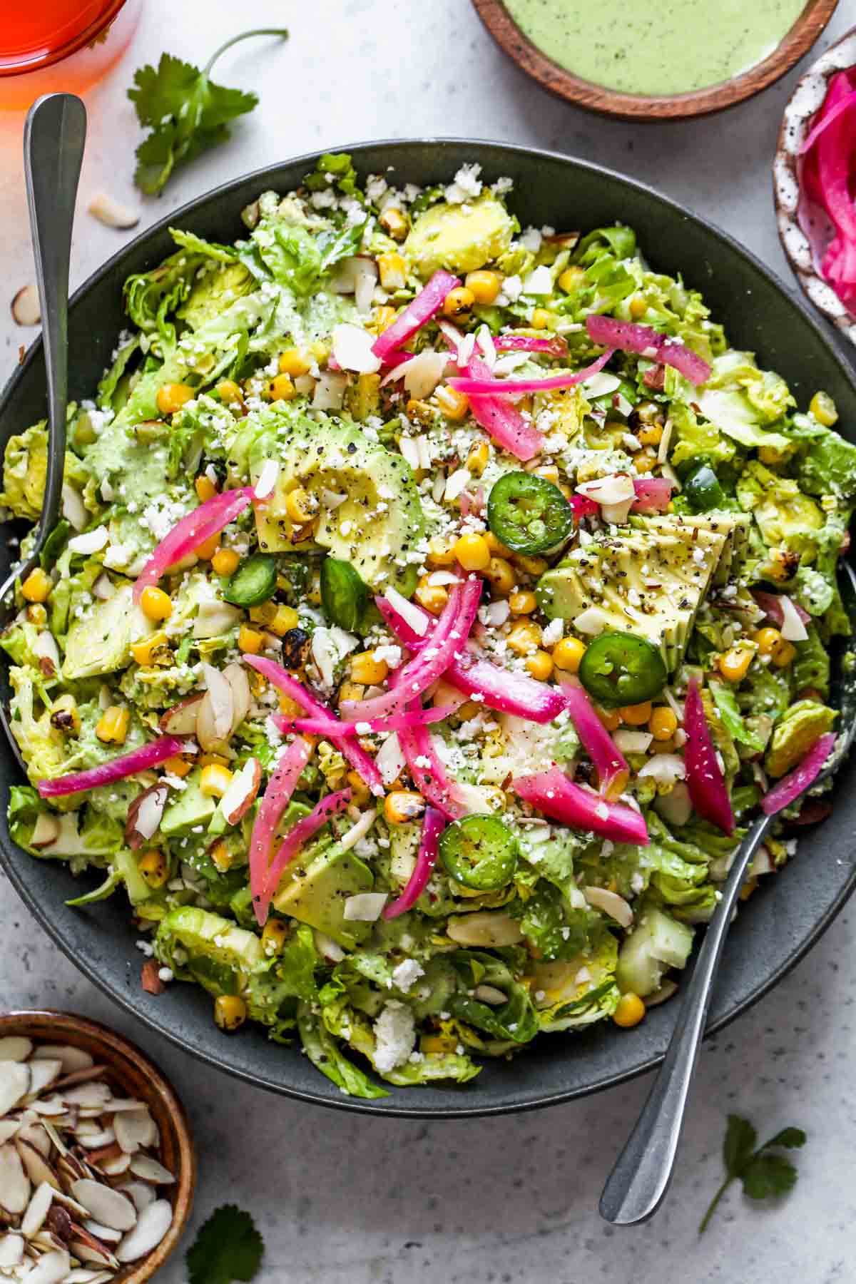 Mexican Brussels sprouts salad assembled in a bowl with serving spoons