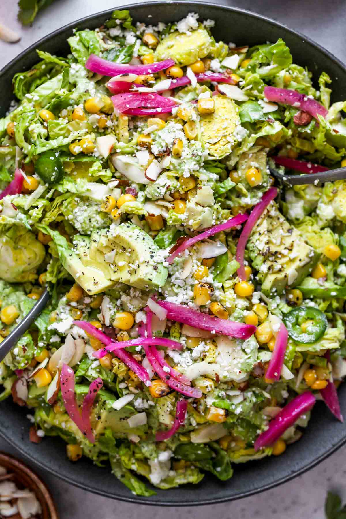 Tossed brussels sprouts salad topped with pickled onions and avocado