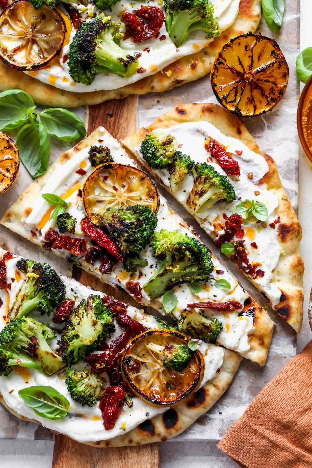 Naan pizza topped with ricotta, broccoli, and tomatoes sliced into thirds