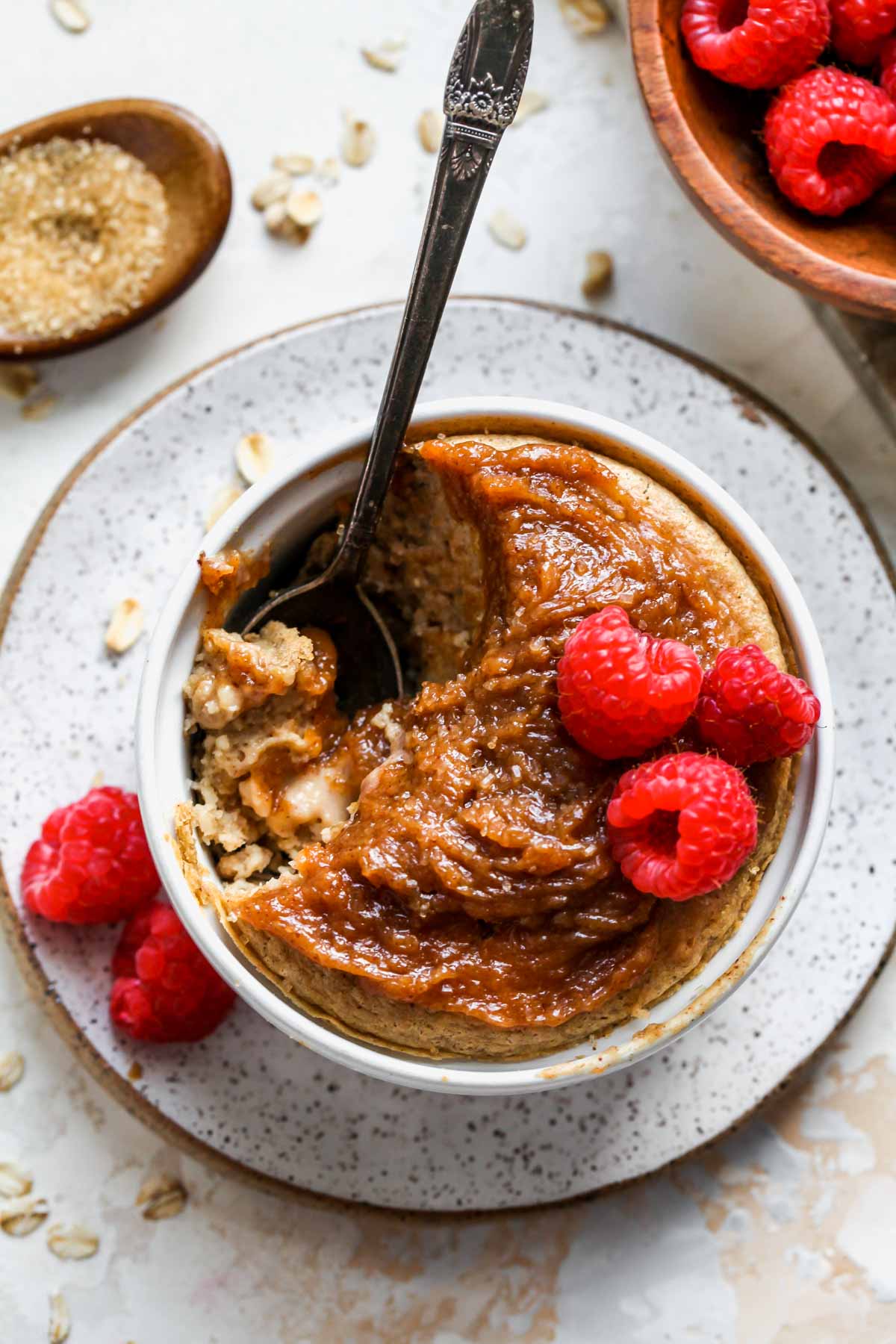 Baked oats for one in a ramekin topped with peanut butter and raspberries