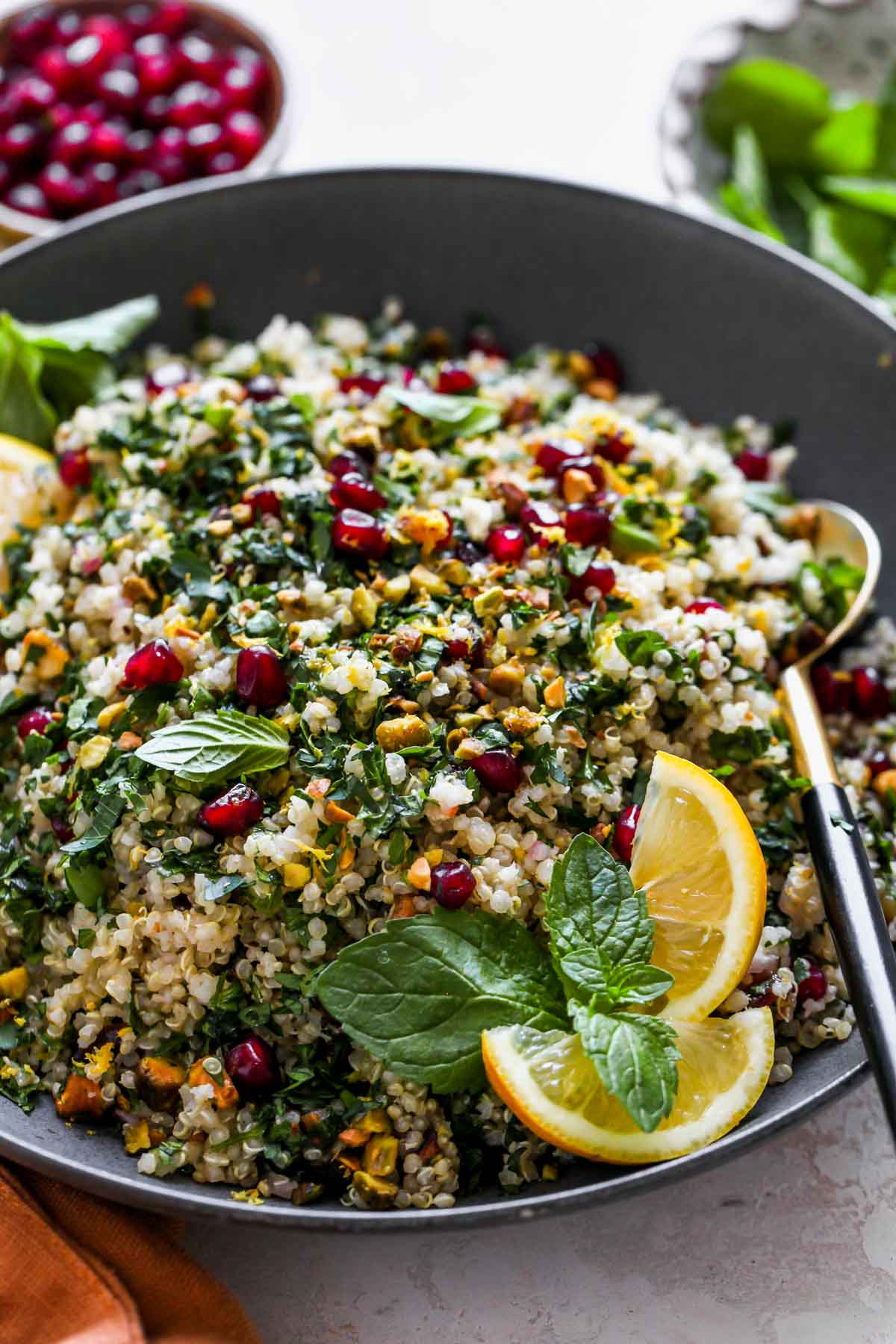 Quinoa Tabbouleh Salad in a black serving bowl with a spoon resting on the right side