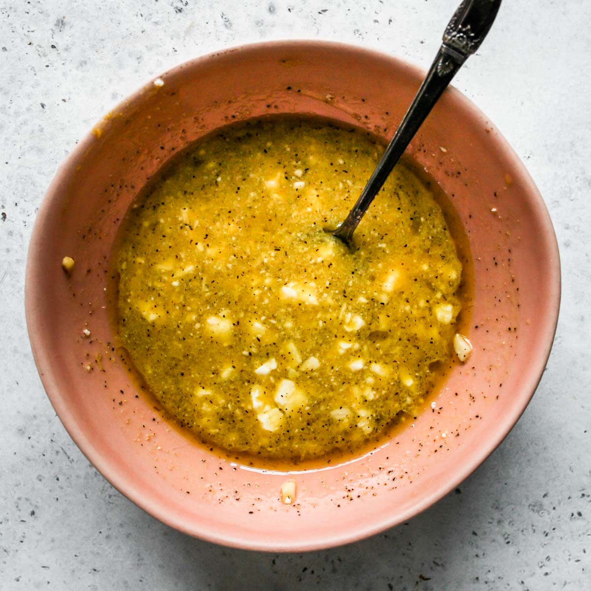 Feta dressing being mixed in a pink bowl