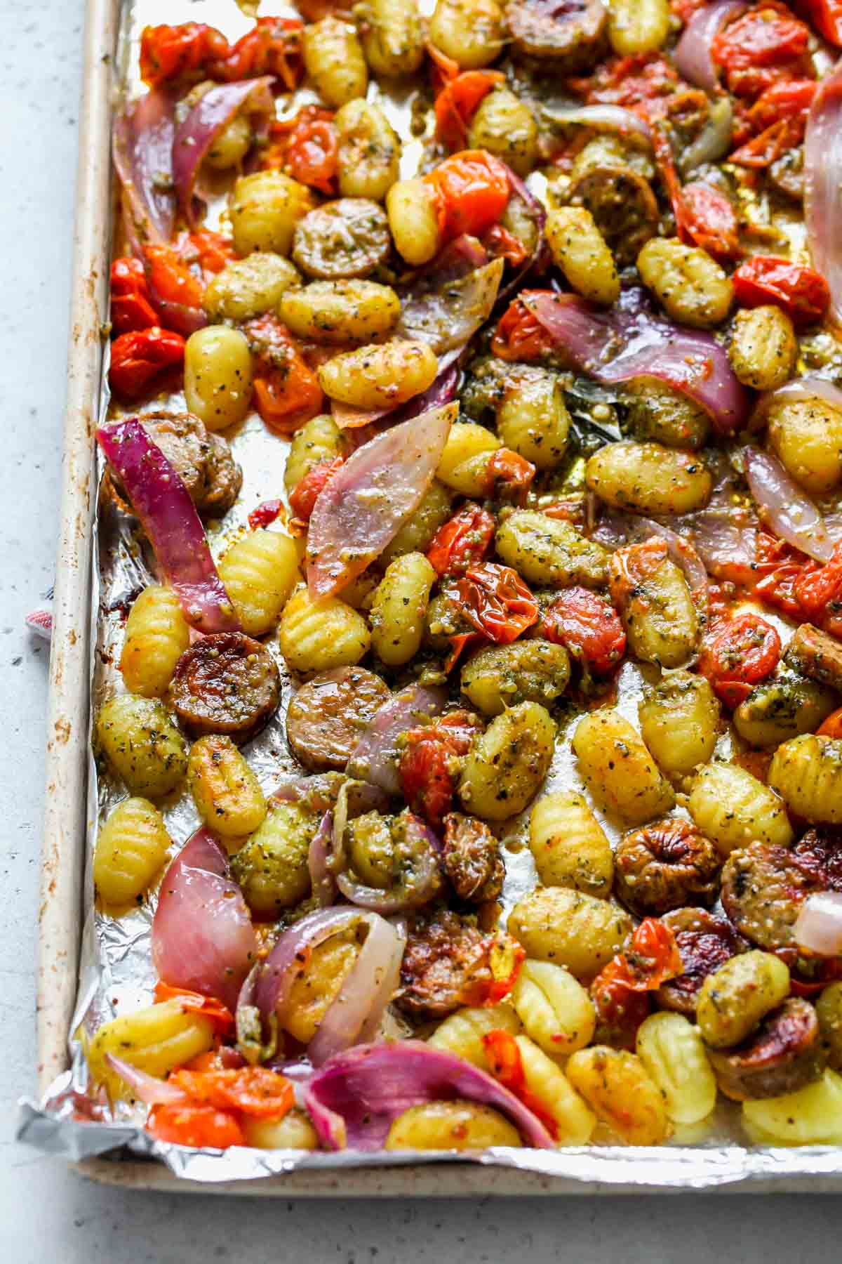 Foil-lined baking sheet with baked pesto gnocchi