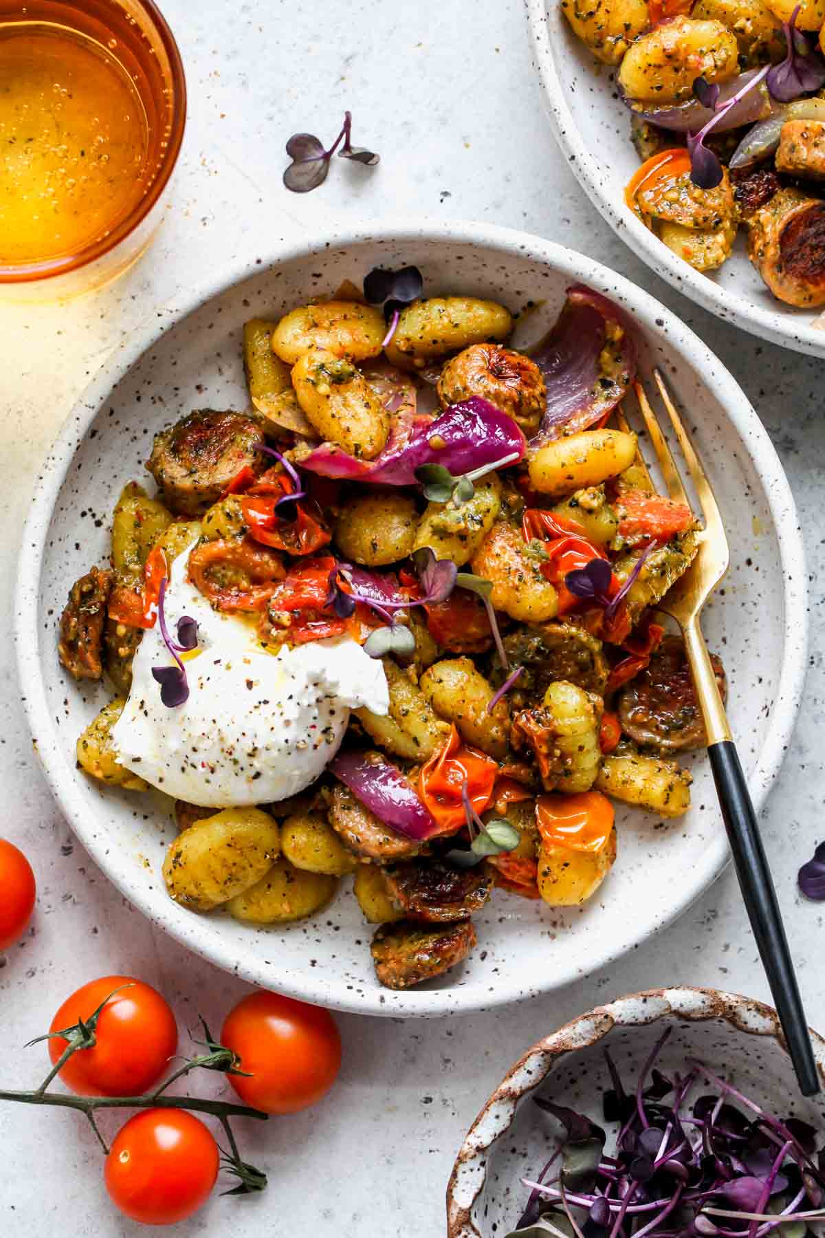 Gnocchi, burrata, and veggies tossed in pesto sauce and served in a white bowl