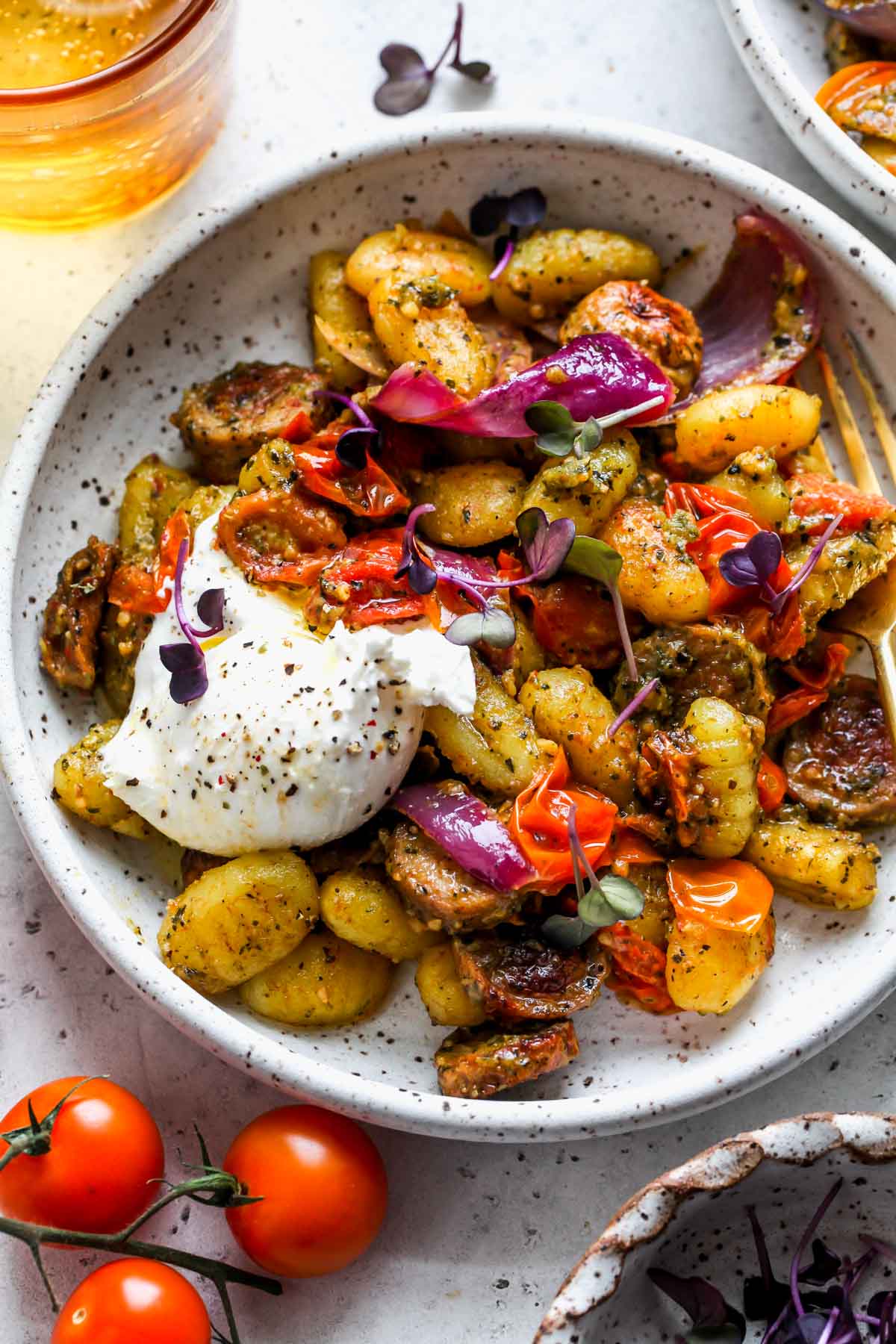 Pesto gnocchi with tomatoes and burrata in a white bowl to showcase summer pasta recipes.
