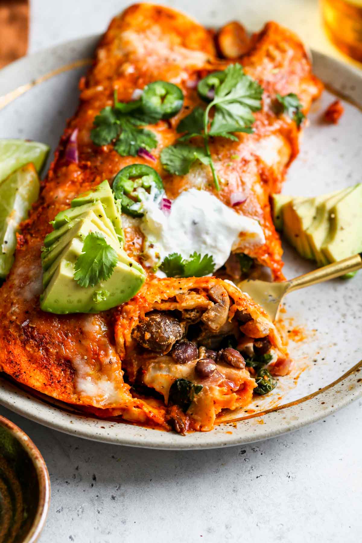 Veggie enchiladas being cut into with a fork to show filling