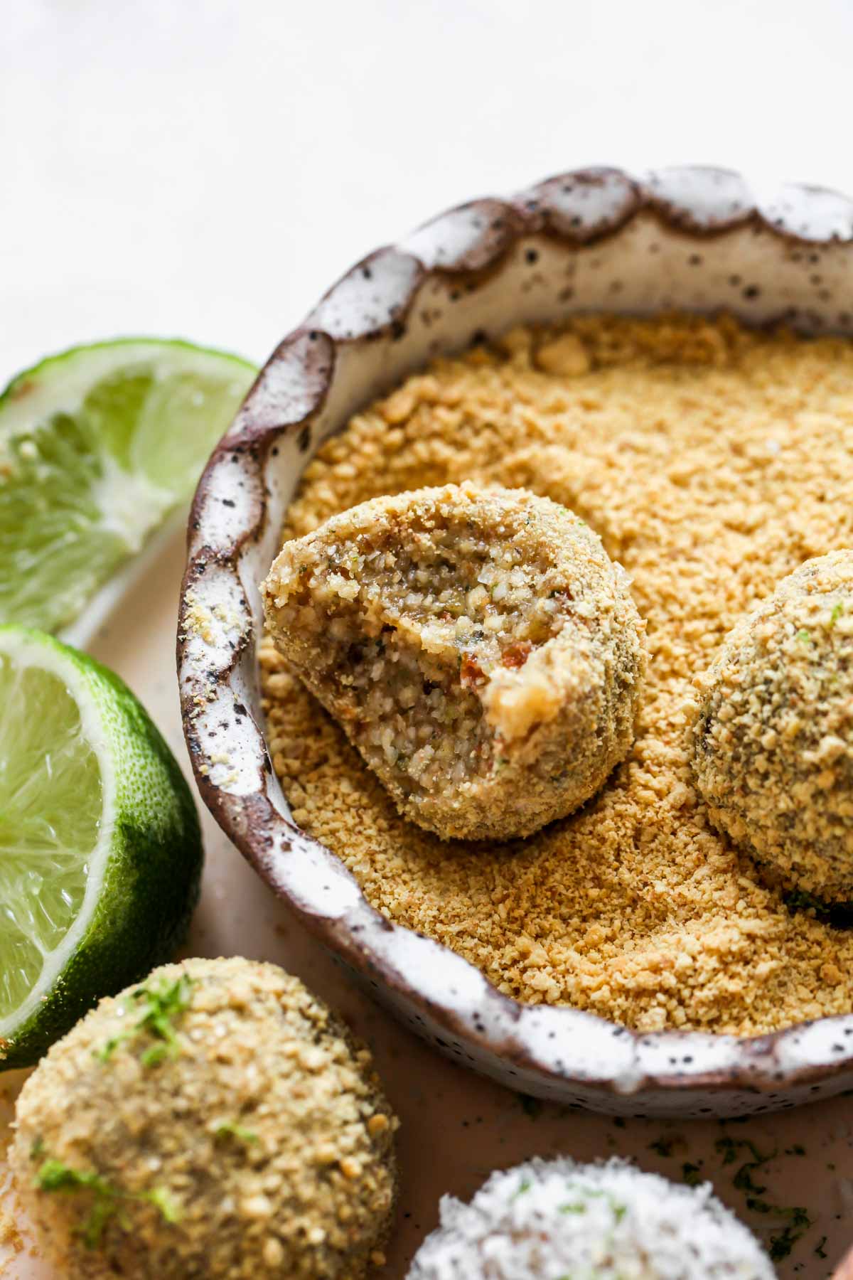 Key lime energy ball being rolled in graham cracker crumbs