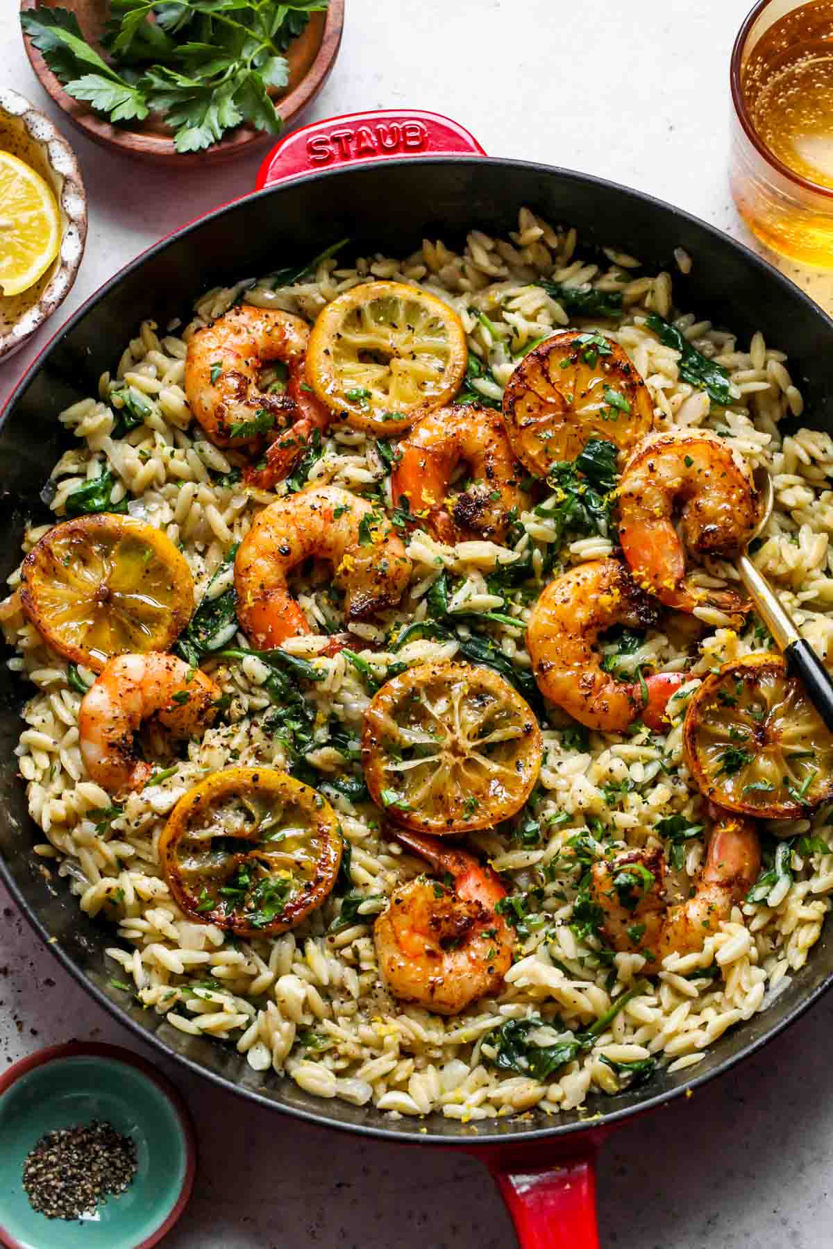 Lemon pepper shrimp and orzo in a cast iron skillet topped with lemon slices.