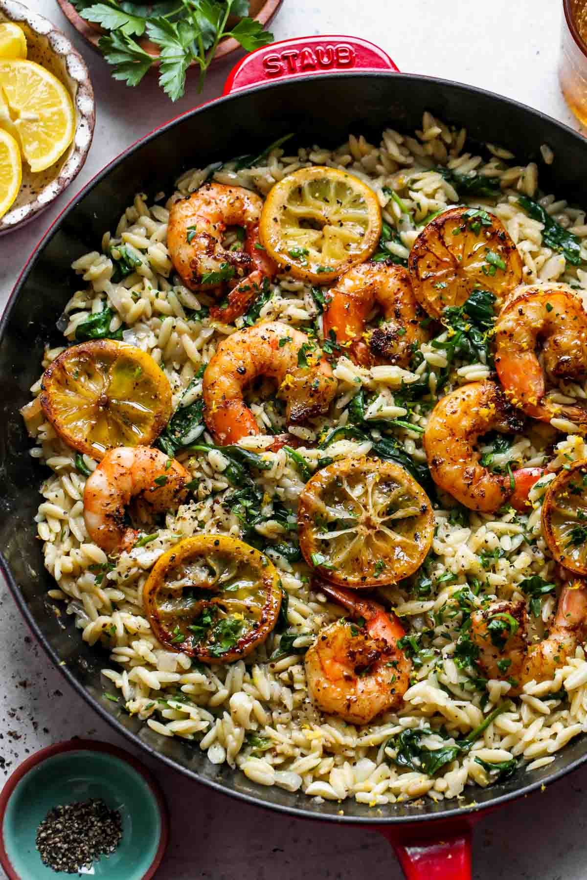 Lemon pepper shrimp and orzo in a pan topped with lemon slices.