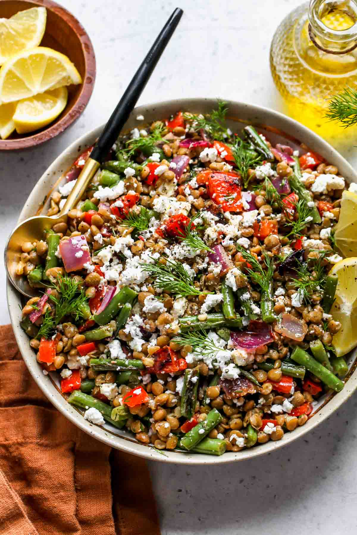 Mediterranean lentil salad styled in a bowl with a serving spoon on the left side.