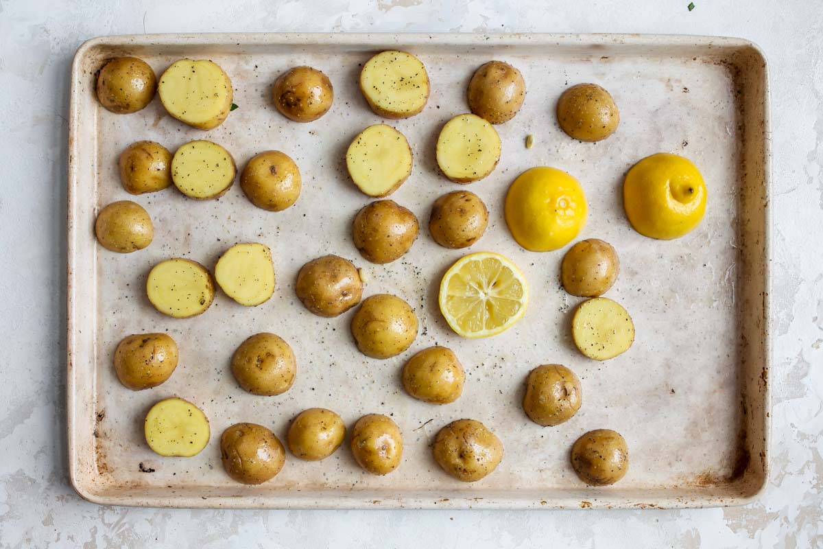 Baby potatoes being roasted on a white baking sheet