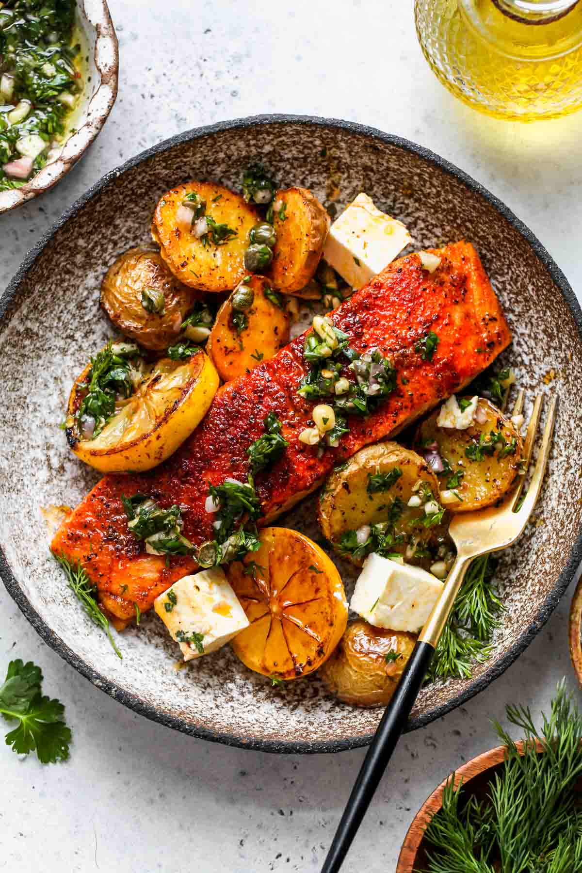 Roasted salmon fillet, potatoes, and chimichurri on a white plate