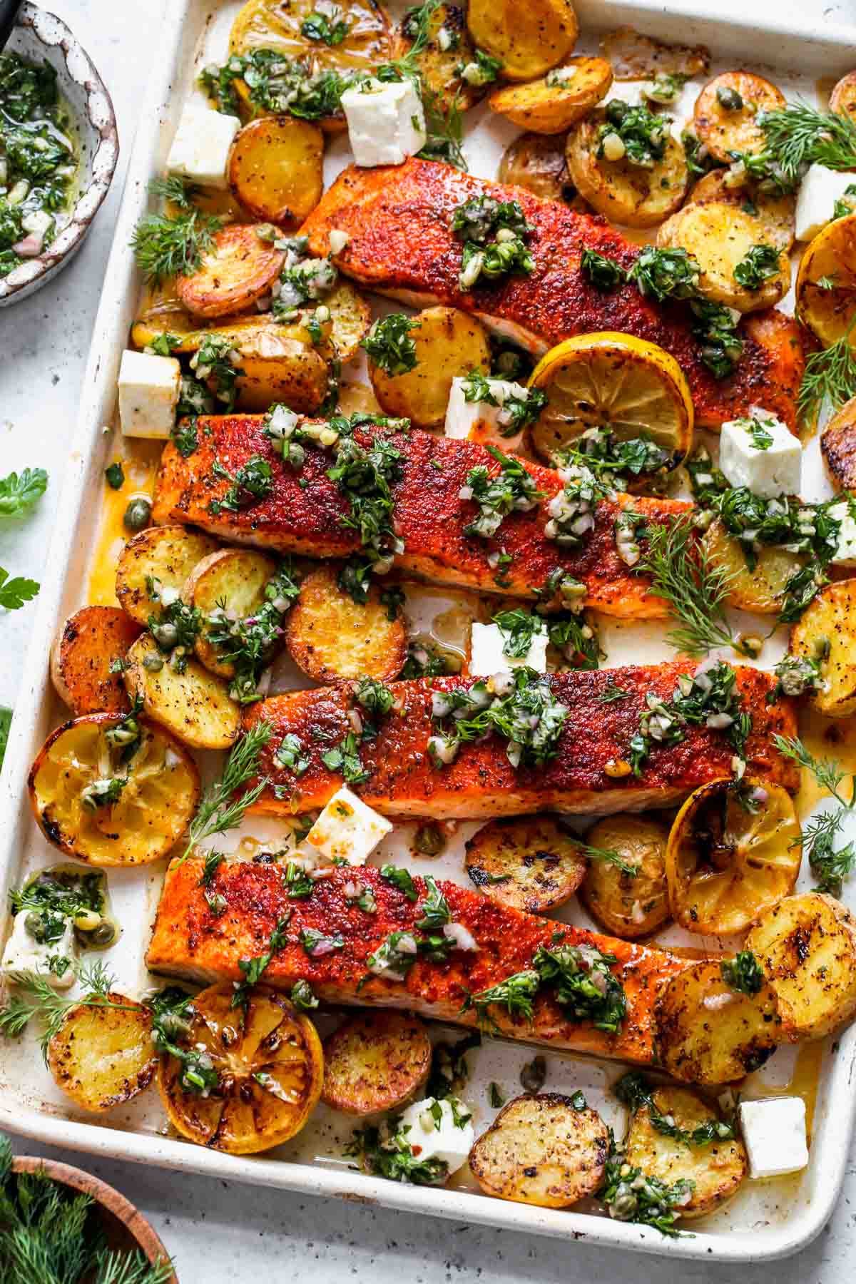 Salmon and potatoes roasted on a sheet pan topped with caper chimichurri