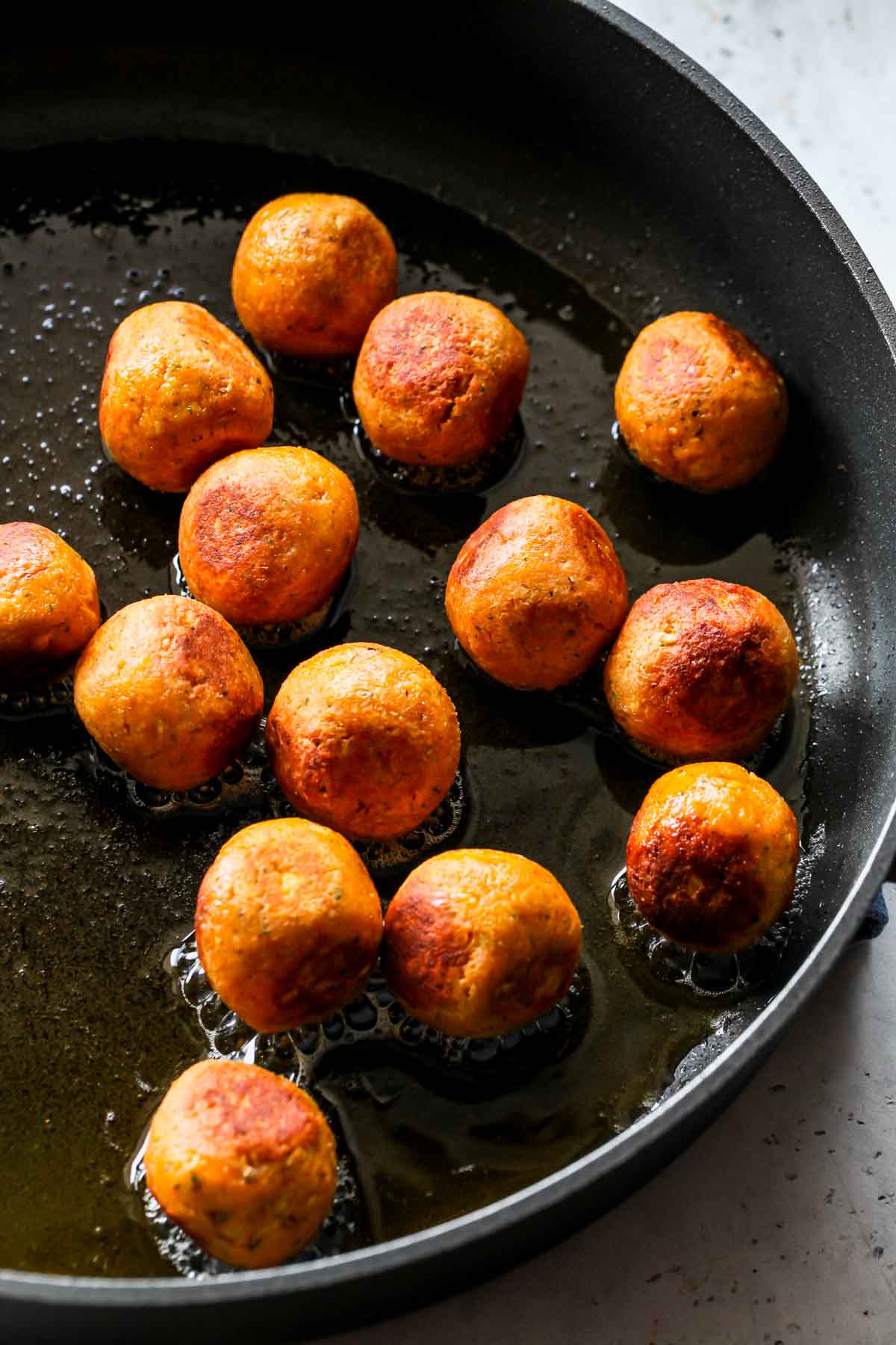 Chickpea meatballs being sautéed in a skillet