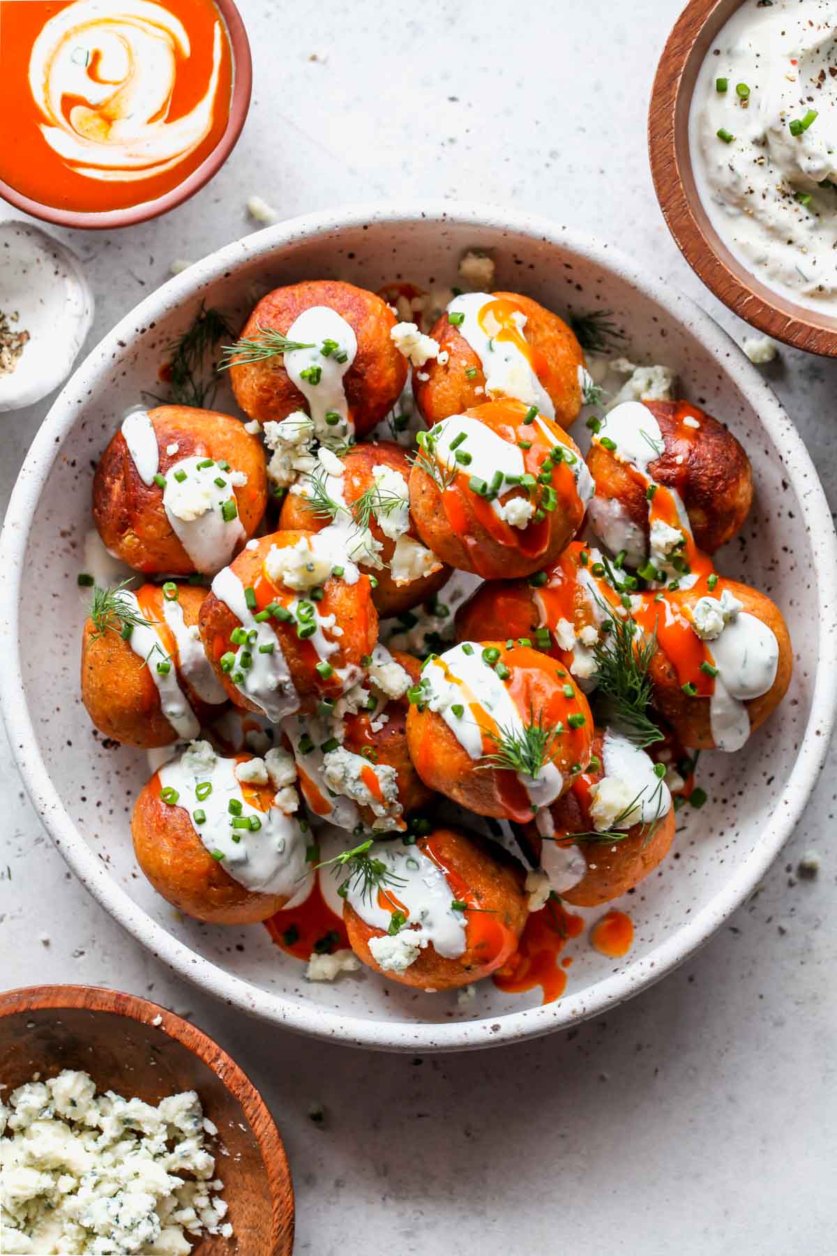 Buffalo chickpea meatballs in a white bowl topped with yogurt ranch and herbs