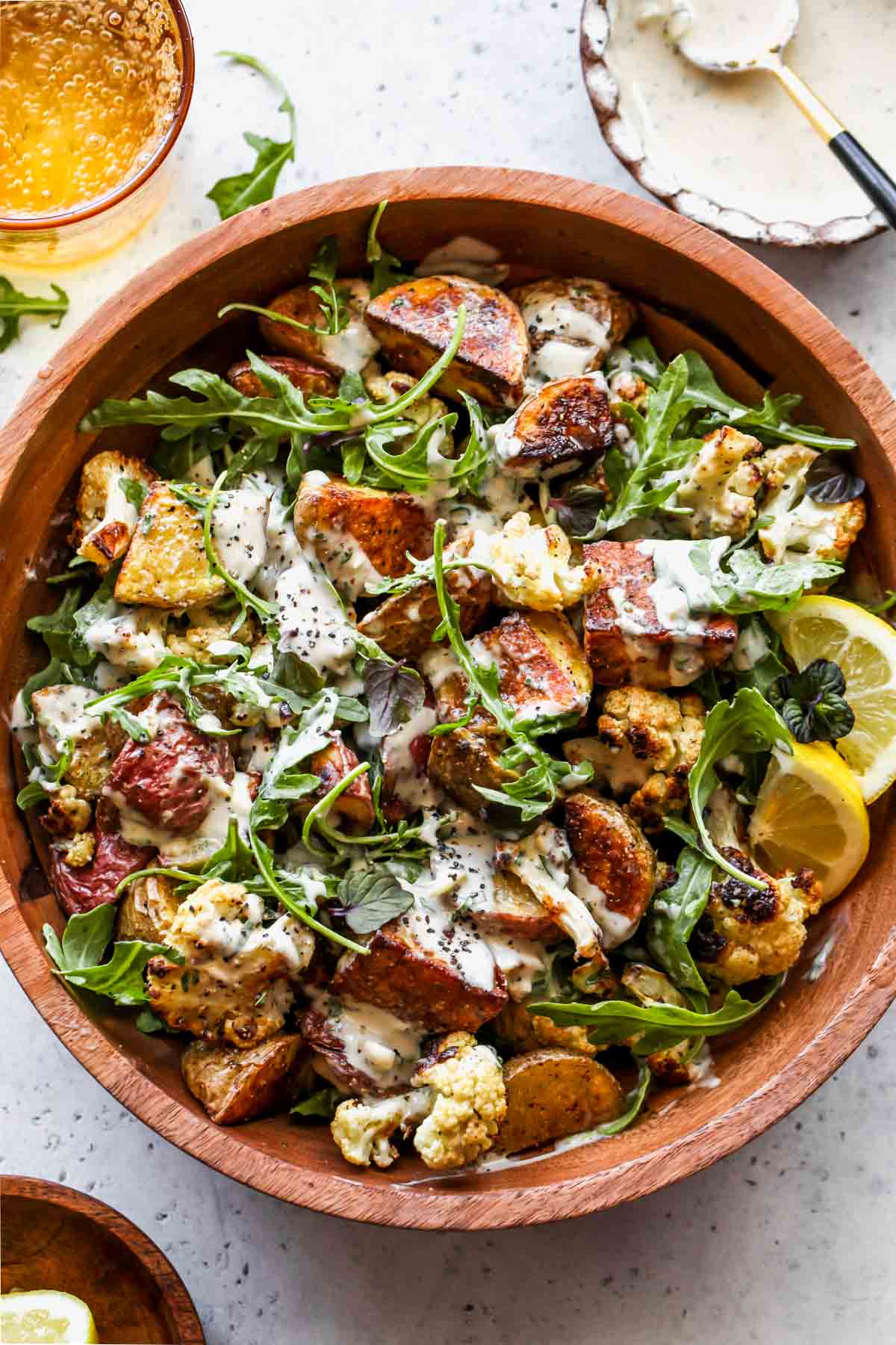 Cauliflower potato salad with arugula and tahini dressing in a wooden serving bowl