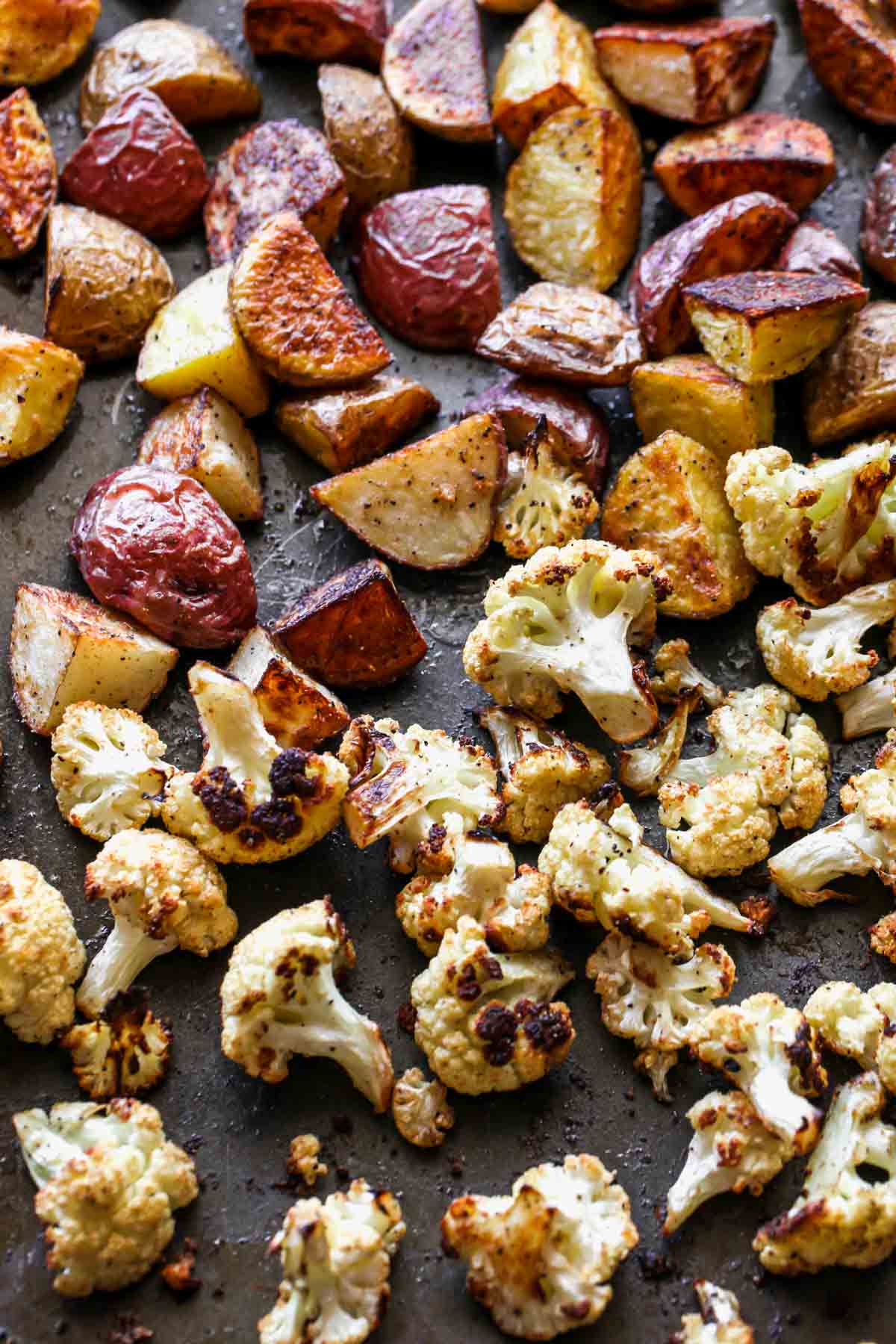 Potatoes and cauliflower florets roasted on a baking sheet