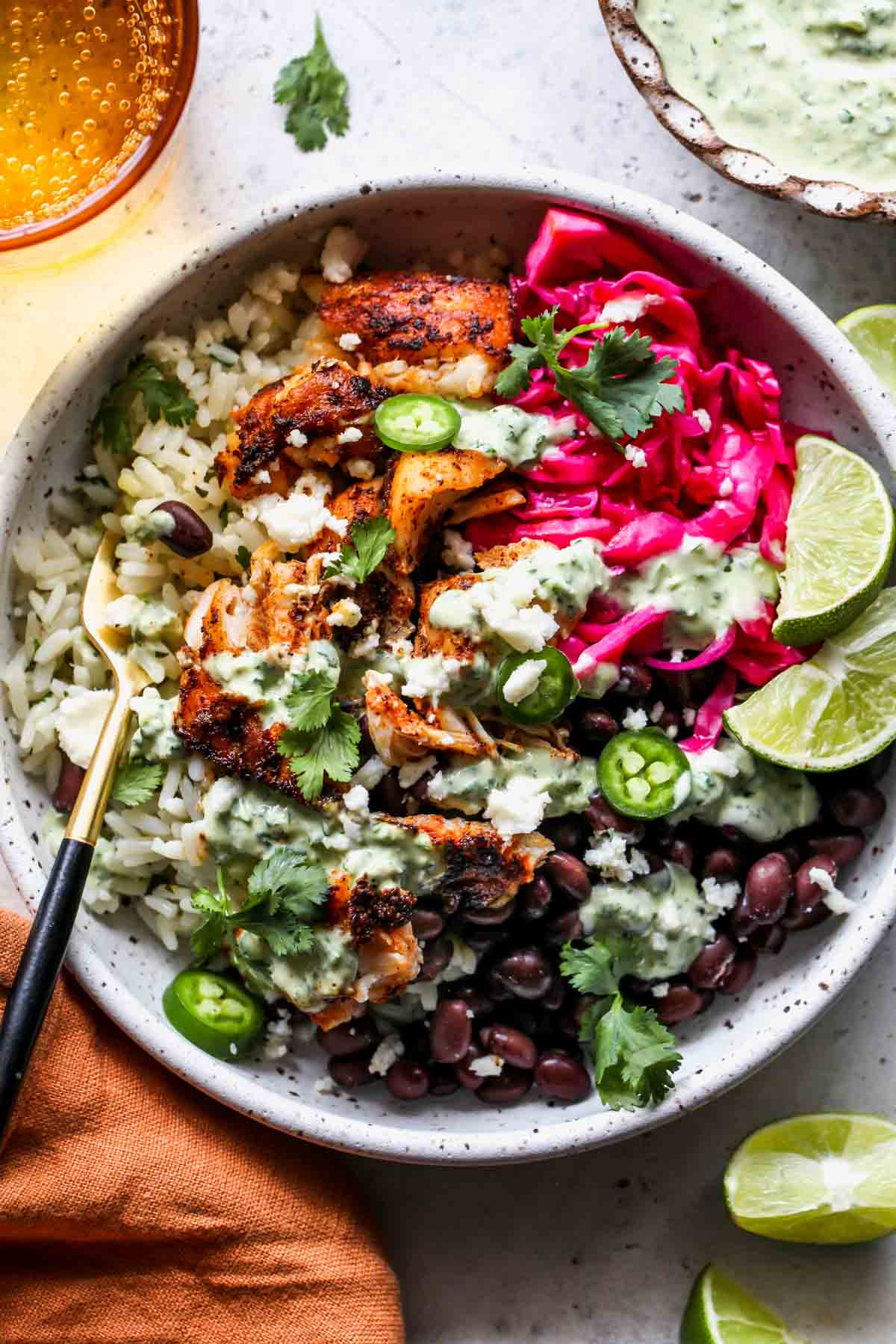 Fish taco bowl topped with jalapeño verde sauce in a white bowl