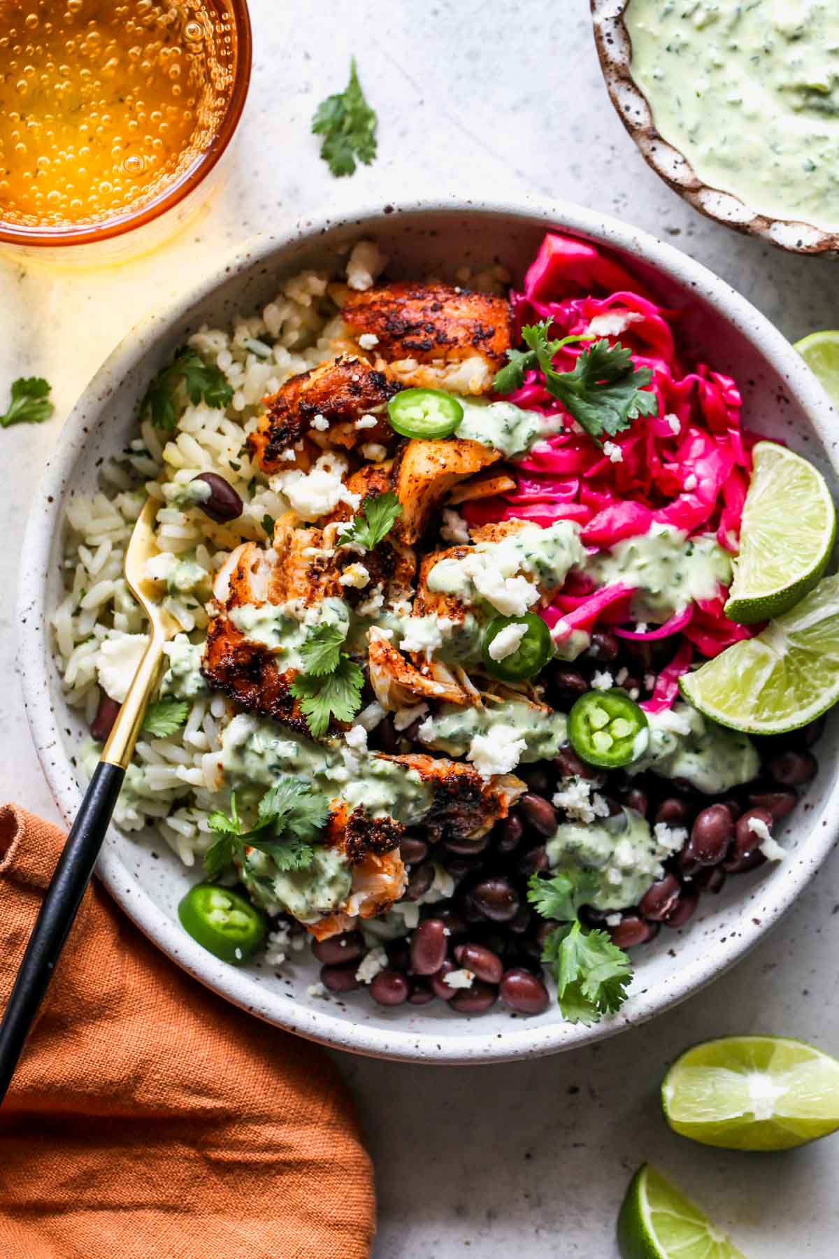 Fish taco bowls with cilantro-lime rice and creamy verde sauce styled in a white bowl