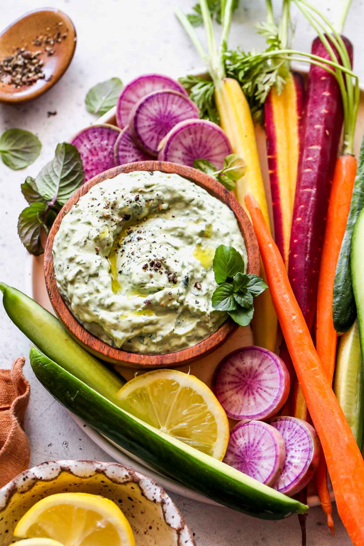 Green goddess avocado dip in a bowl on a tray of veggies