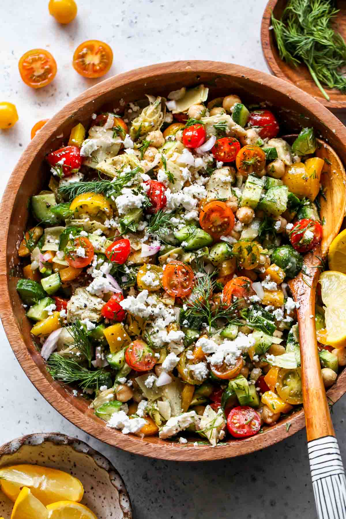 Mediterranean Chickpea Salad in a bowl with a serving spoon resting on the right side