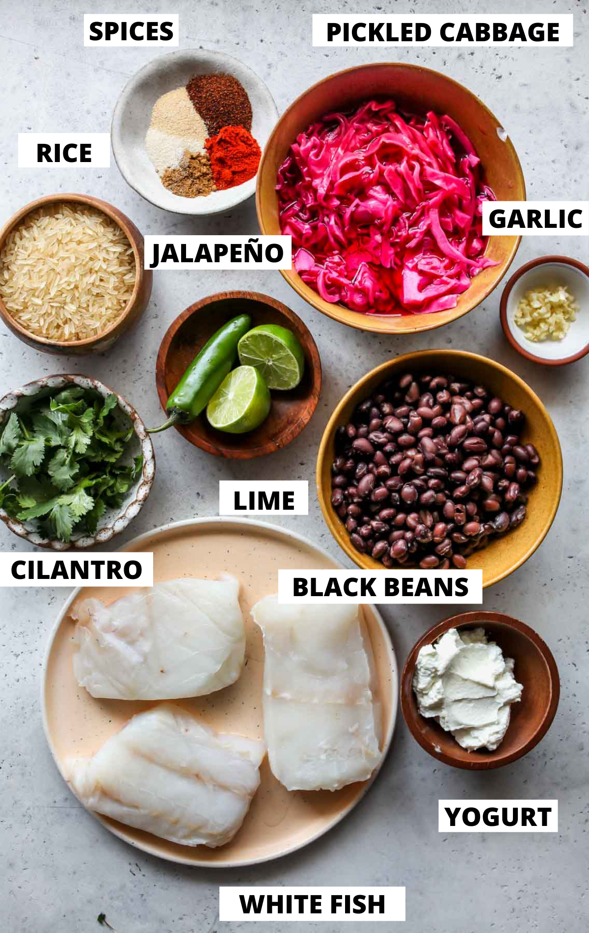 Recipe ingredients in separate bowls on a grey board with labels