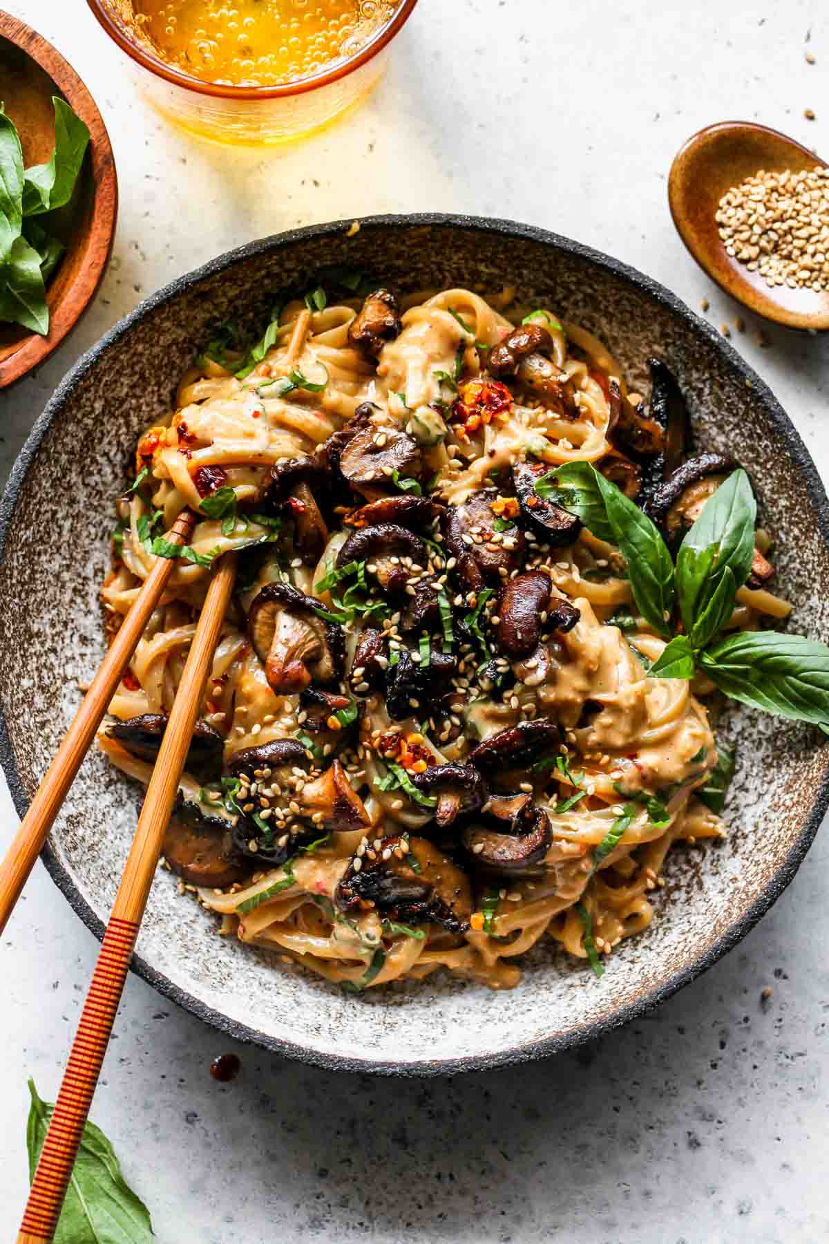 Peanut noodles in a bowl topped with roasted mushrooms and basil