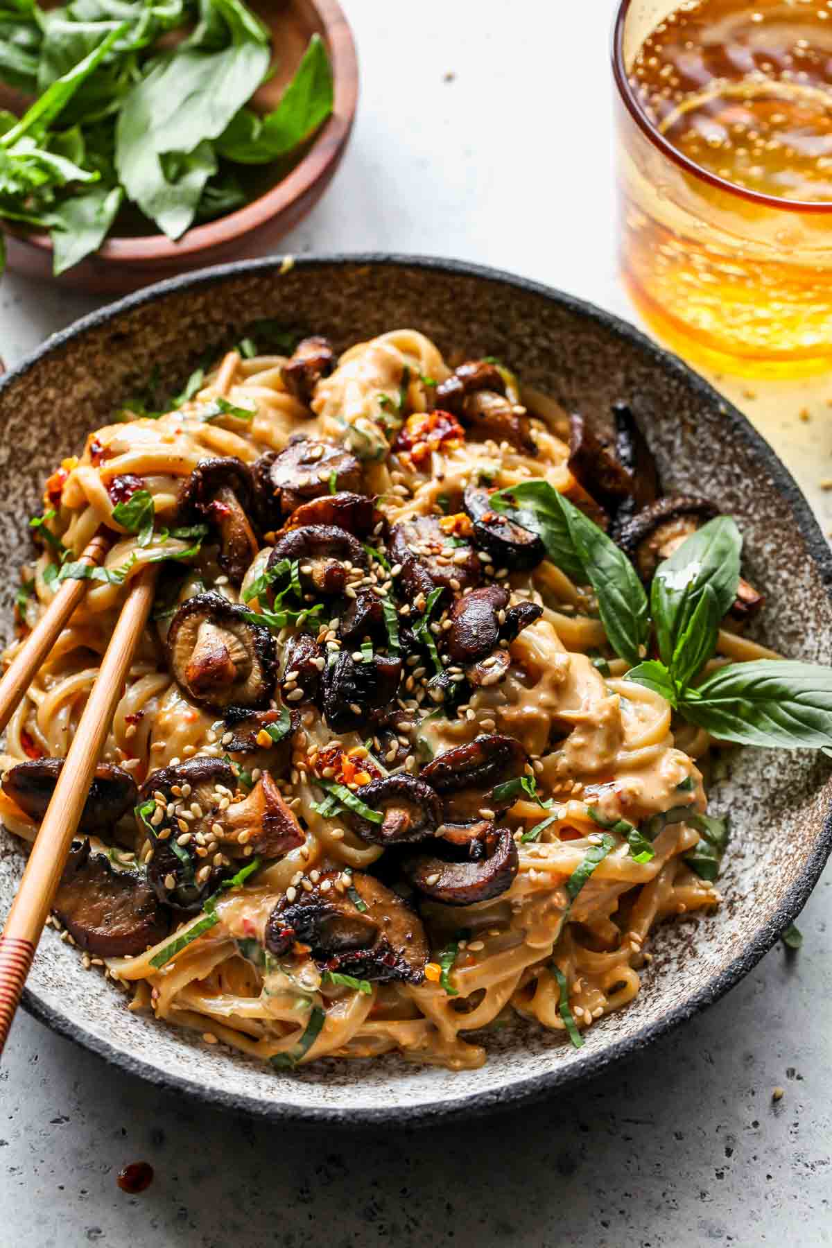 Brown rice noodles tossed in peanut sauce and topped with roasted mushrooms in a bowl