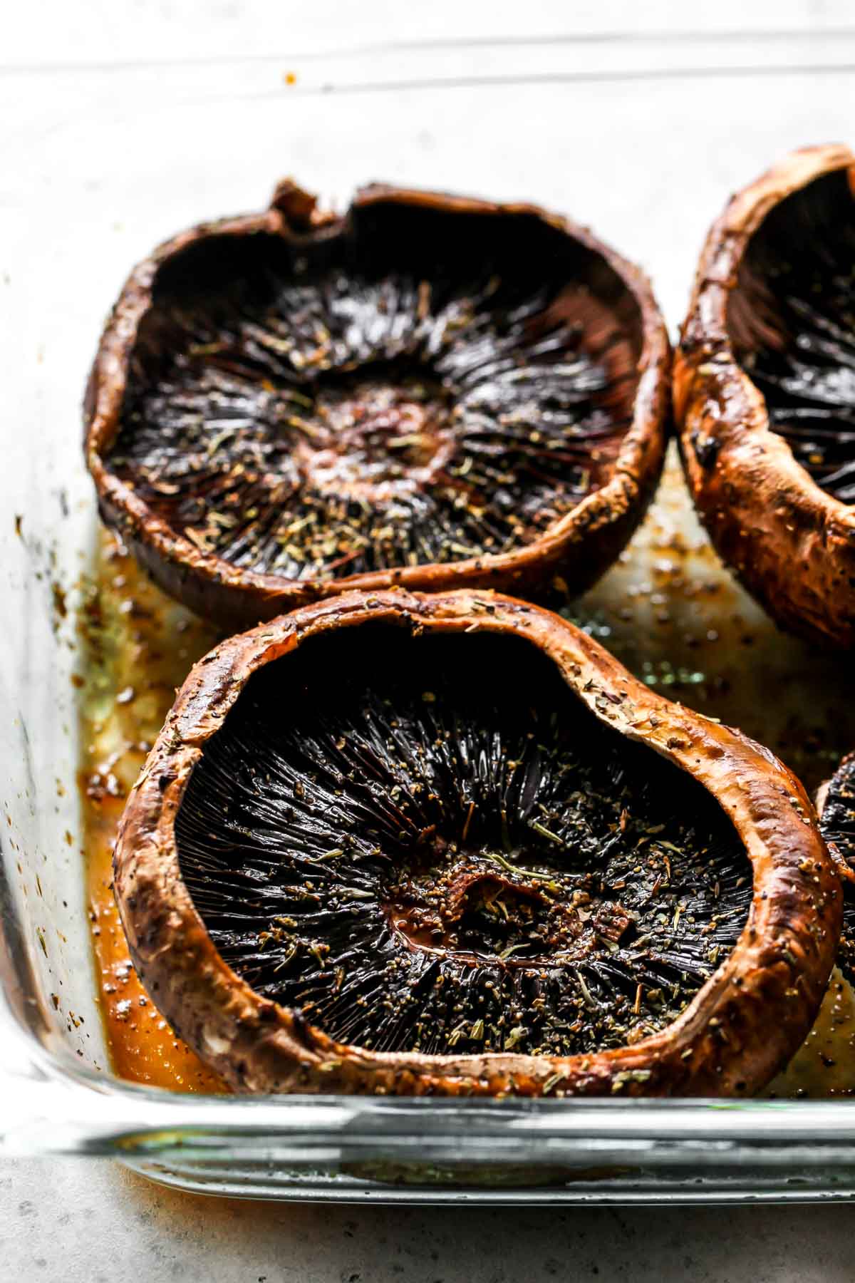 Portobello mushrooms being marinated in a baking pan