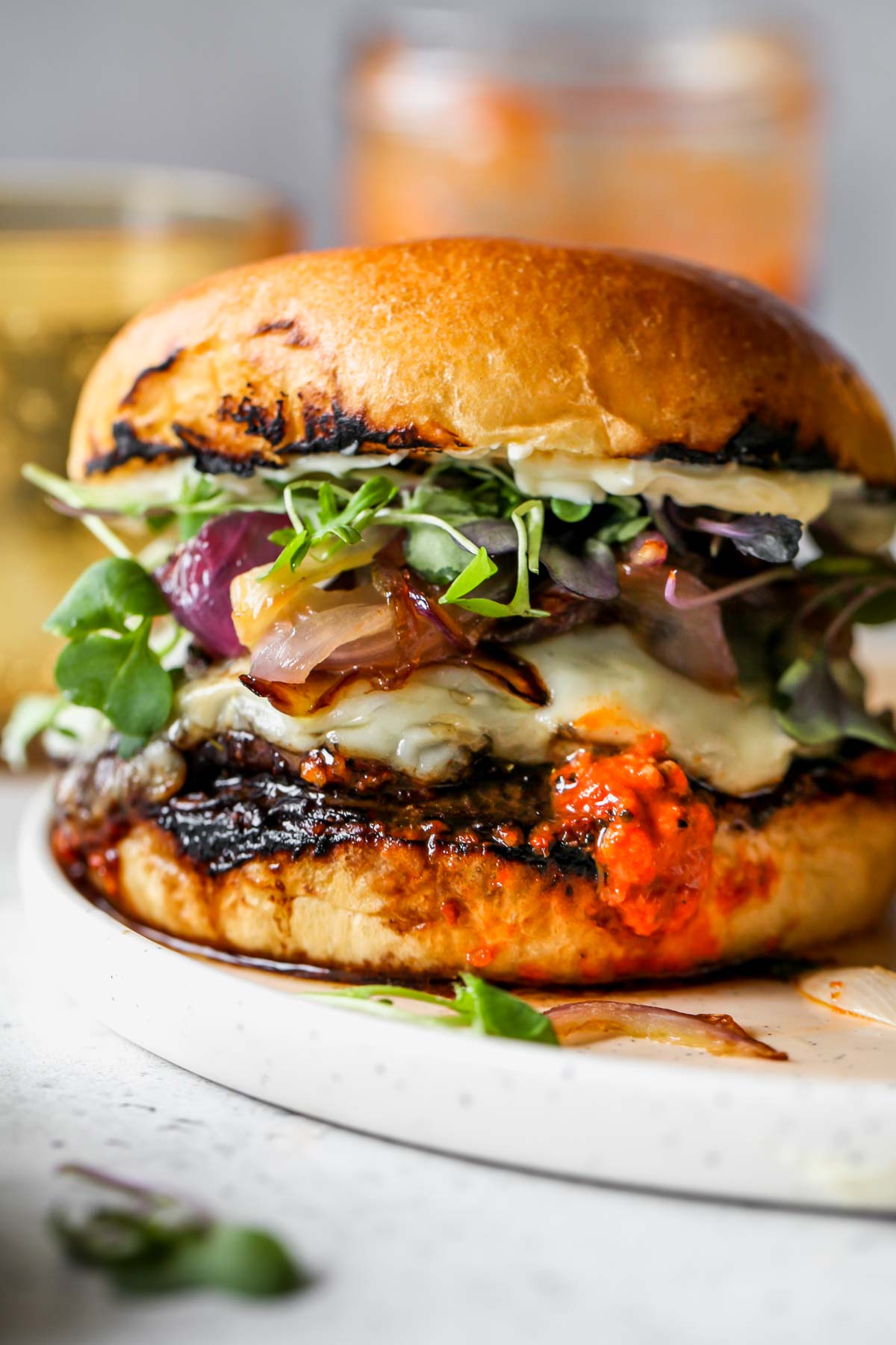 Portobello burger with romesco sauce styled in a bun on a white plate
