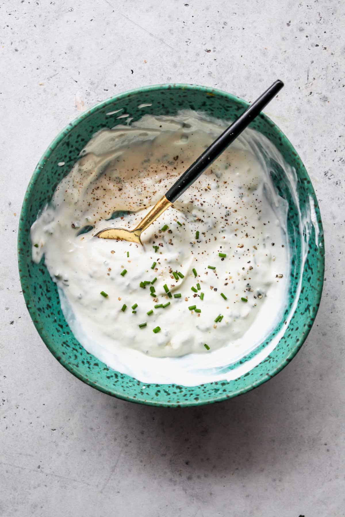 Garlic aioli being mixed in a blue bowl