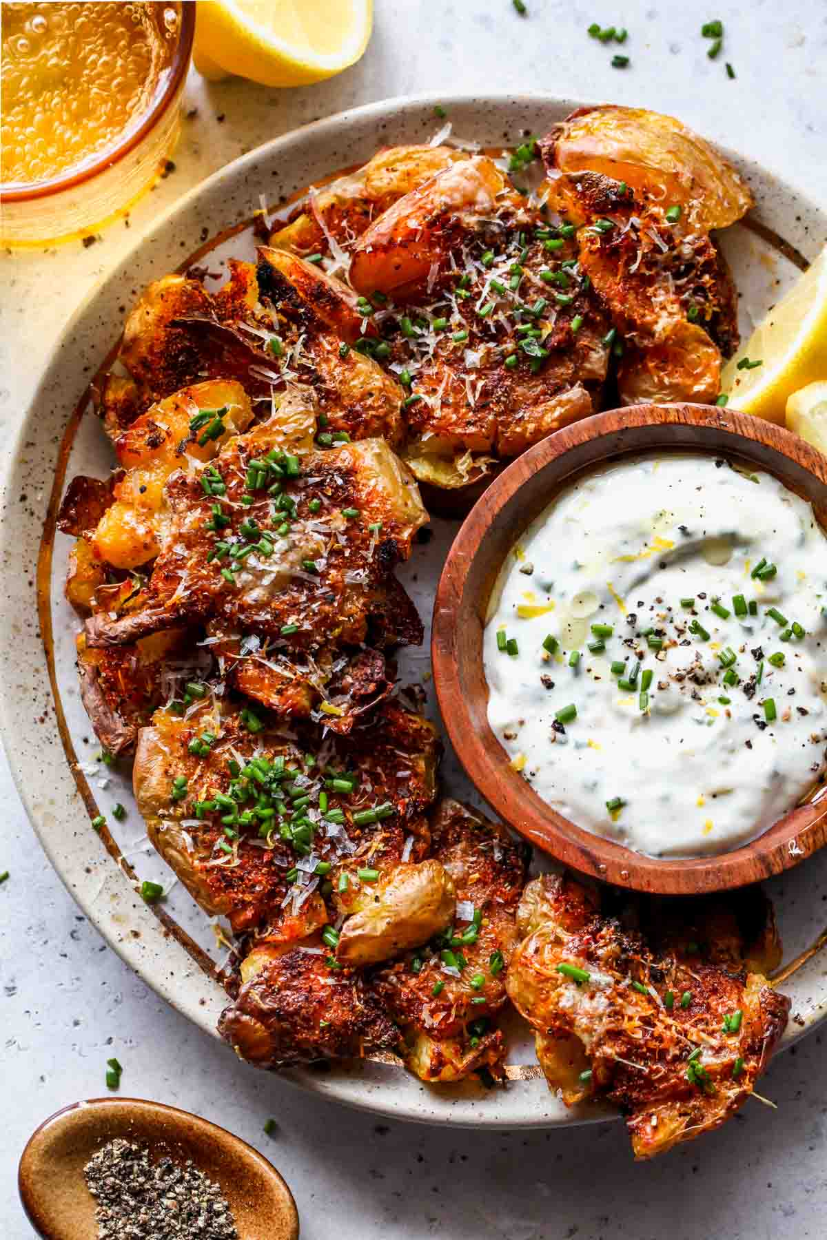 Smashed potatoes on a platter with a bowl of garlic aioli