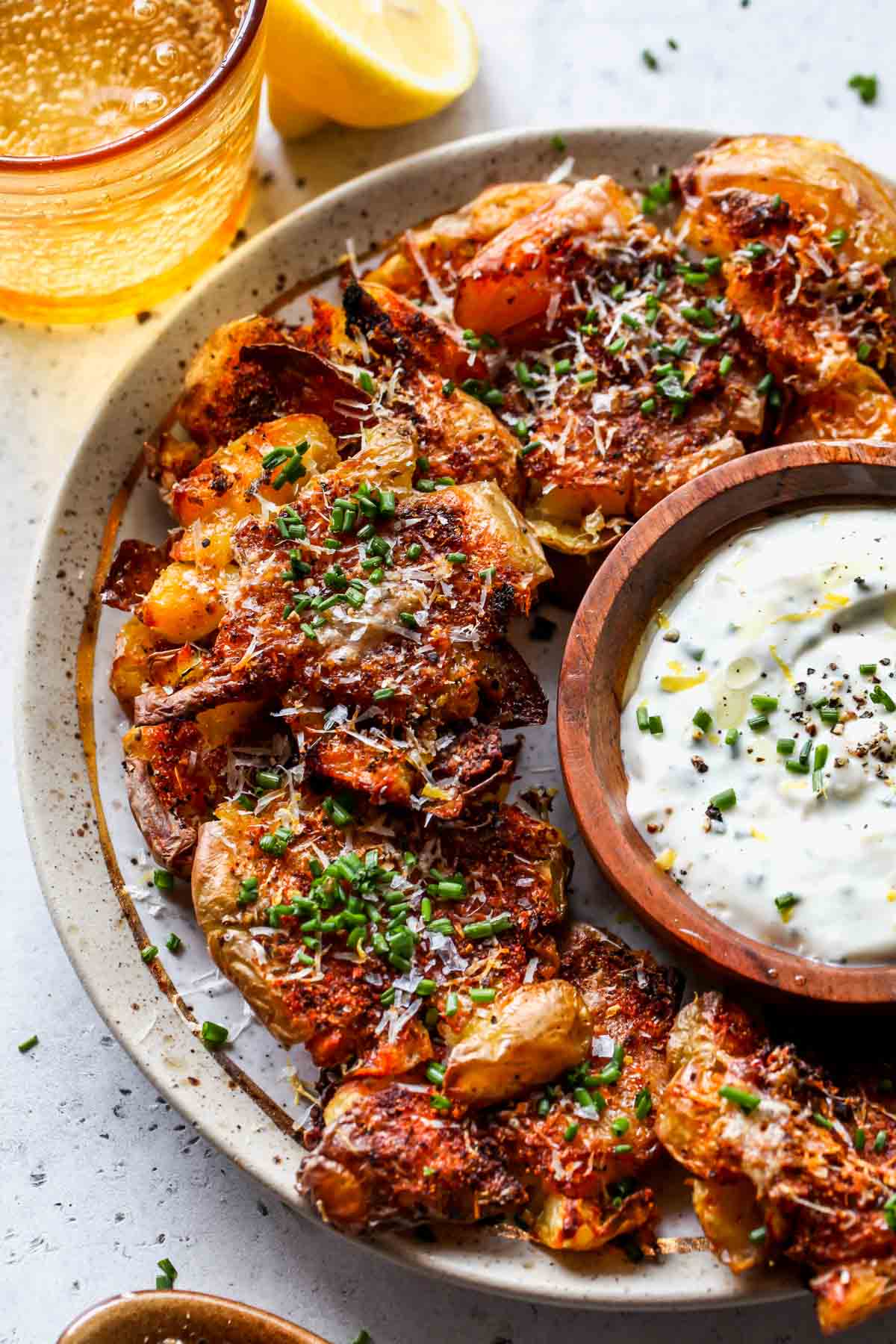 Smashed potatoes arranged on a platter with garlic sauce for dipping